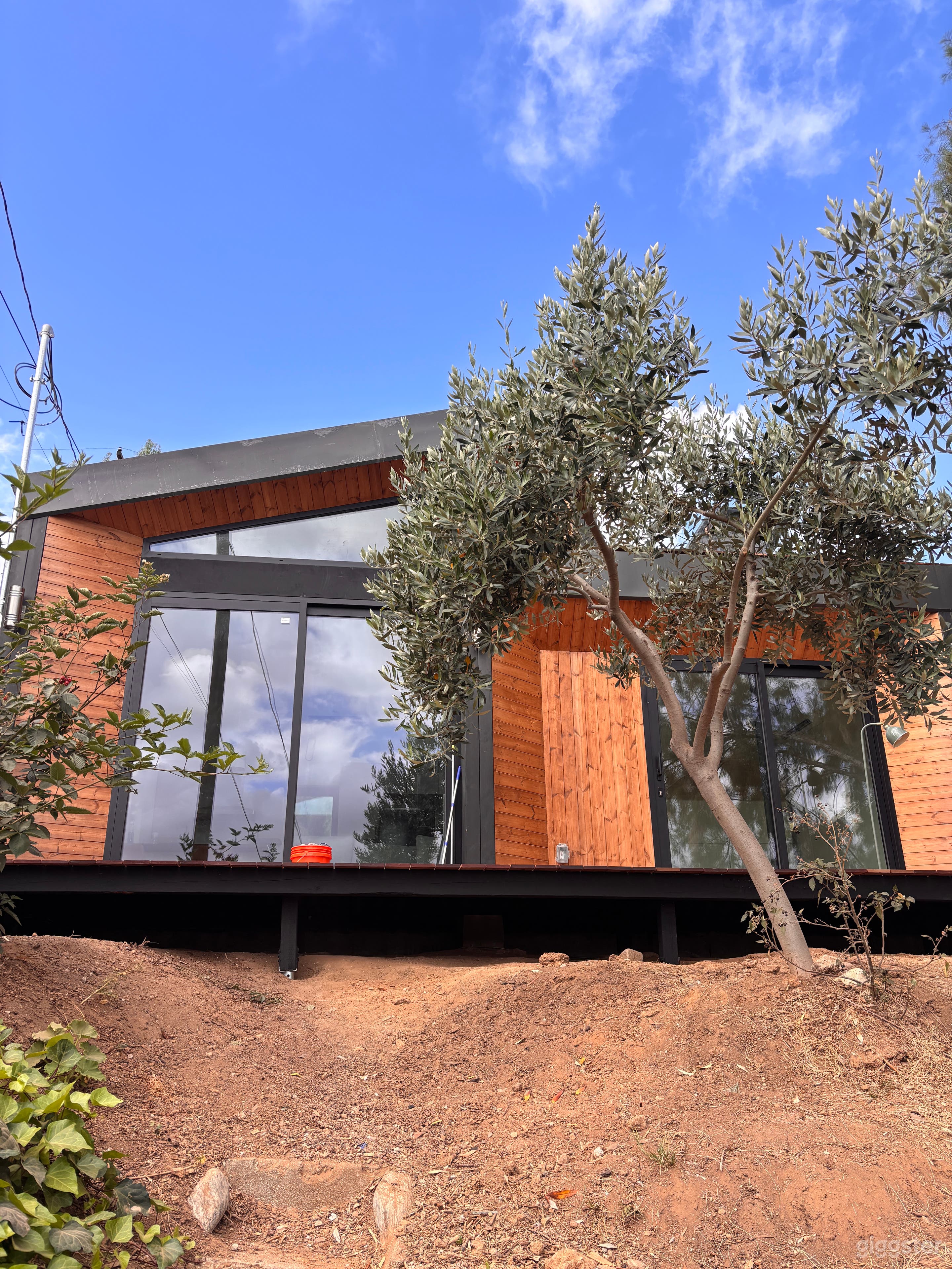 Warm modern exterior with wood siding, clean architectural lines, large windows, natural light, and lush California landscaping. A stylish cinematic setting for film, TV, photo shoots, branded content, and intimate creative productions.