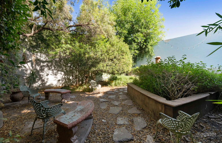  Oasis | Outdoor Studio Space: Lush greenery, rustic accents, stone pathways, string lights, versatile layouts for various shoots. 