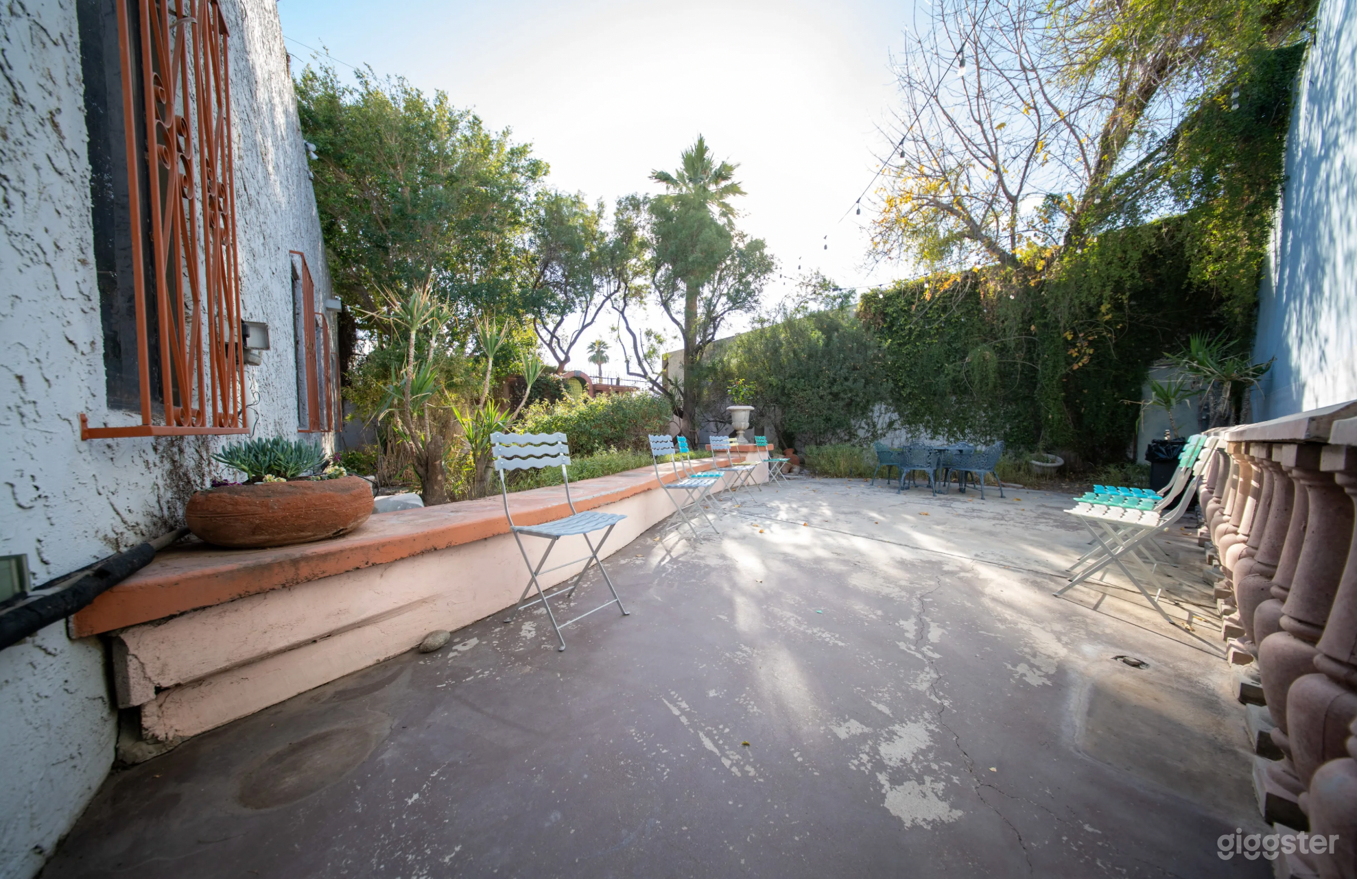 Oasis | Outdoor Studio Space: Lush greenery, rustic accents, stone pathways, string lights, versatile layouts for various shoots.
