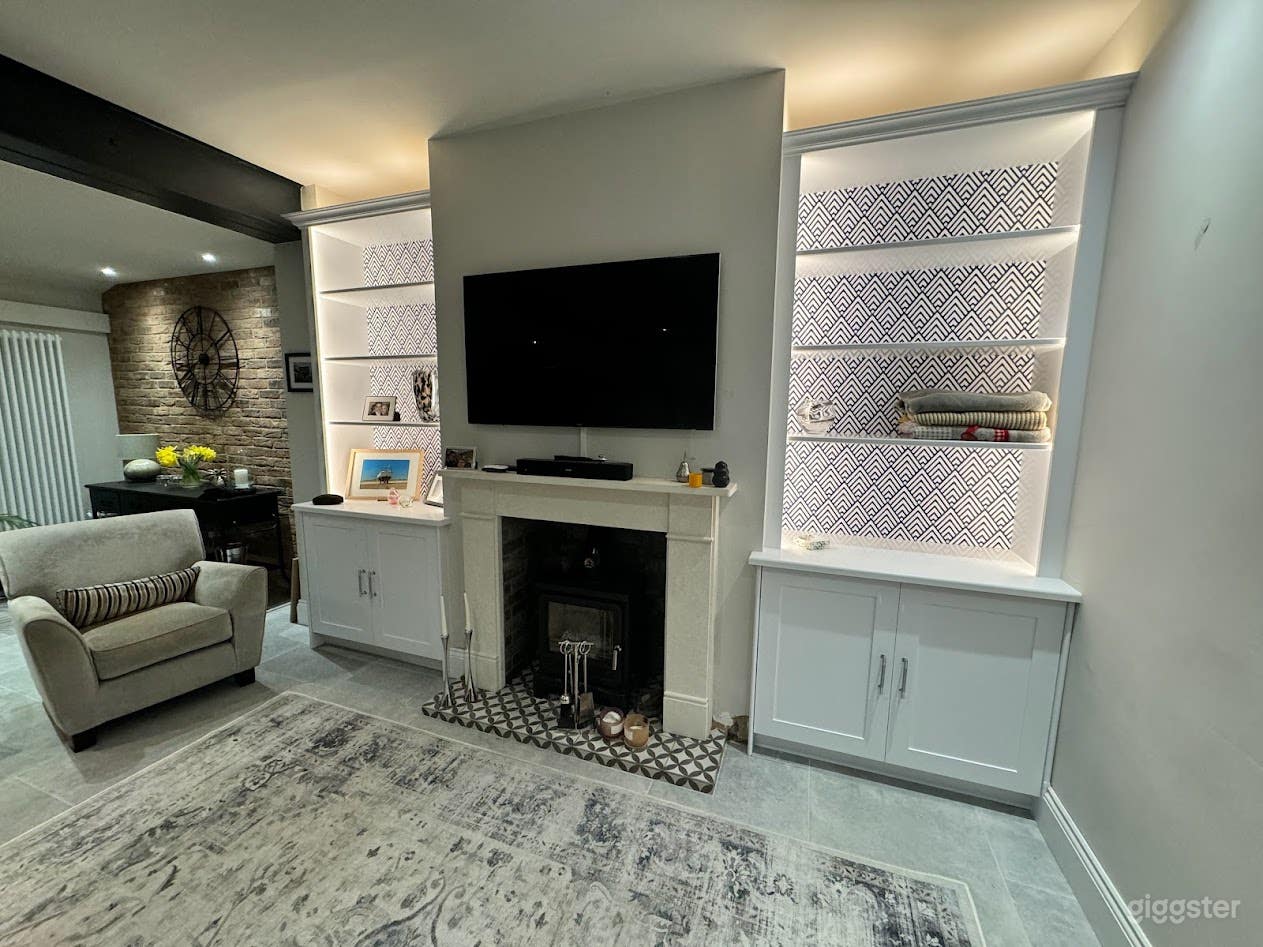 Chic lounge area featuring an exposed brick wall, log burner, and bespoke shelving with geometric accents. Warm lighting and modern textures make it ideal for intimate scenes and lifestyle shoots.