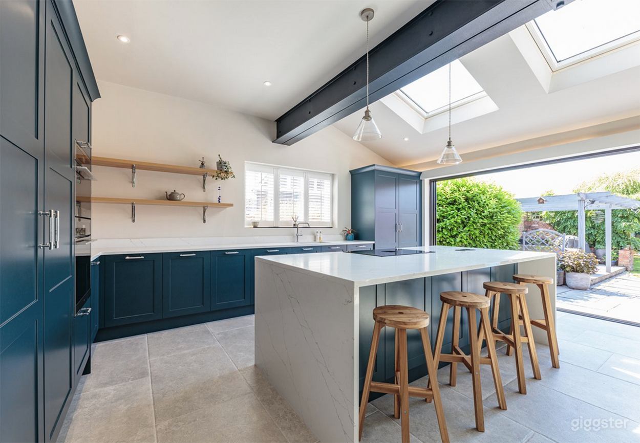 Stylish open-plan kitchen featuring rich cabinetry, quartz counters, and an exposed steel beam. Skylights and sliding doors open to a south-facing garden—perfect for natural light shoots and lifestyle scenes.