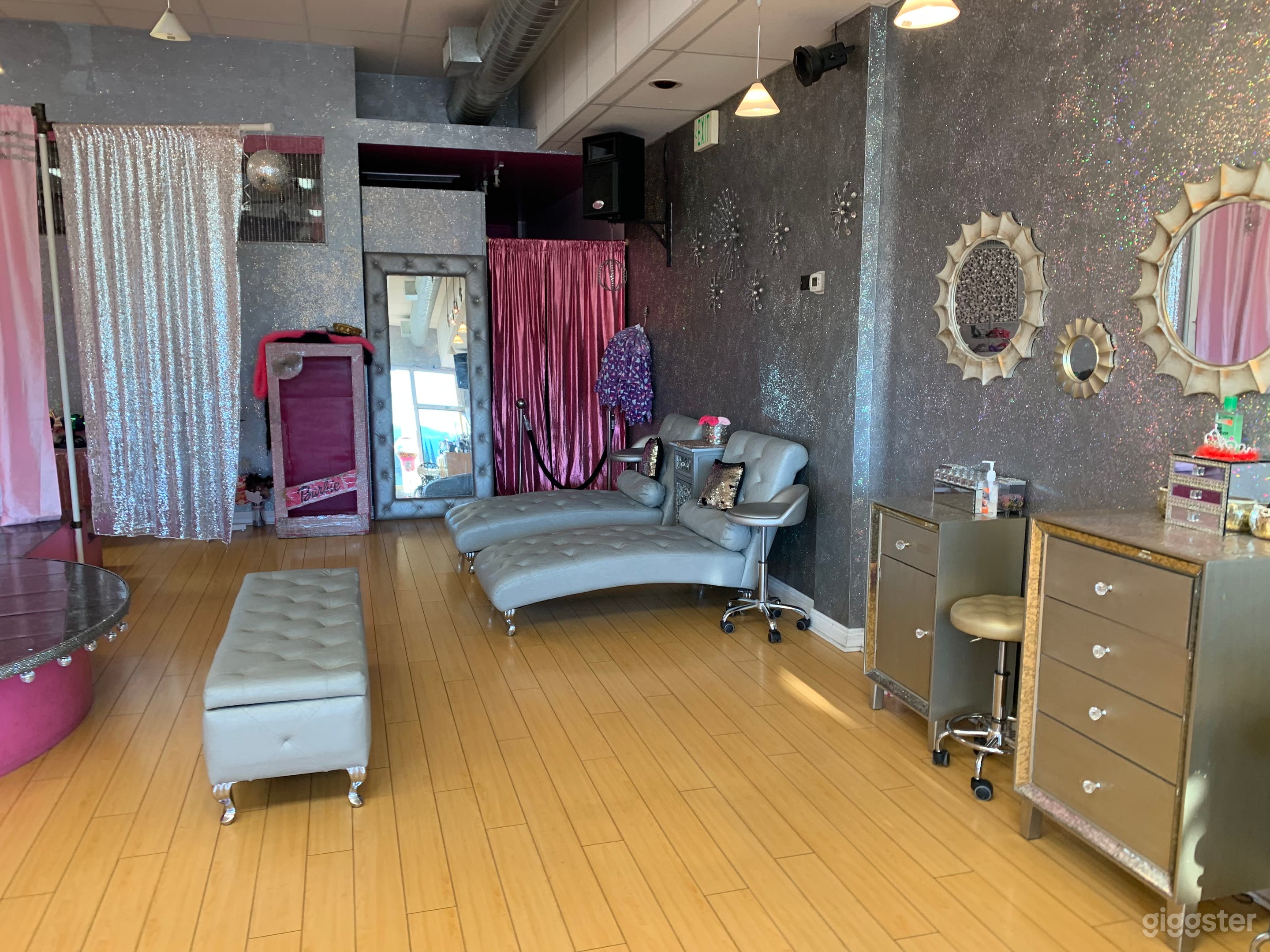 Fifth side of spa view incudes hair and makeup stations, facial beds and dressing are behind hot pink Curtains.