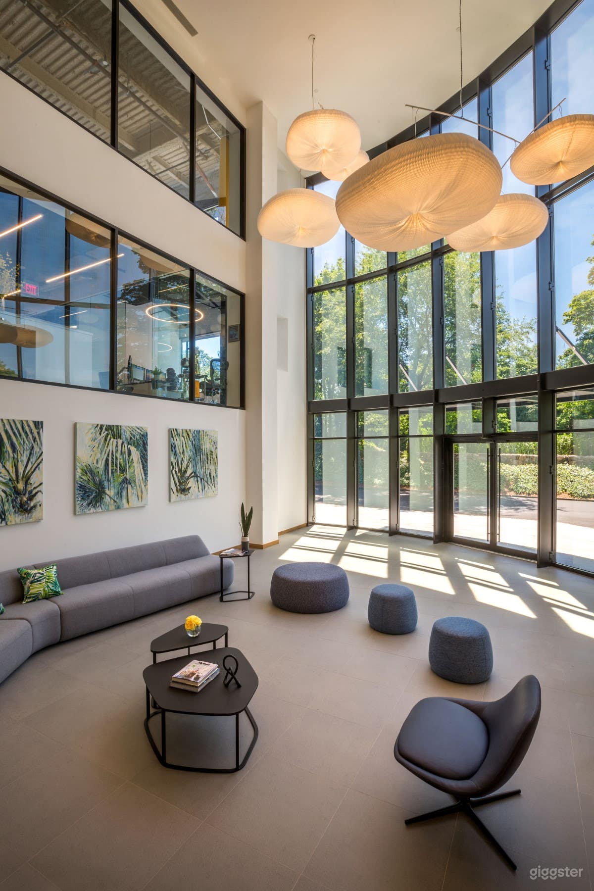 Multi-story atrium lobby with high ceilings and tall windows, seating
