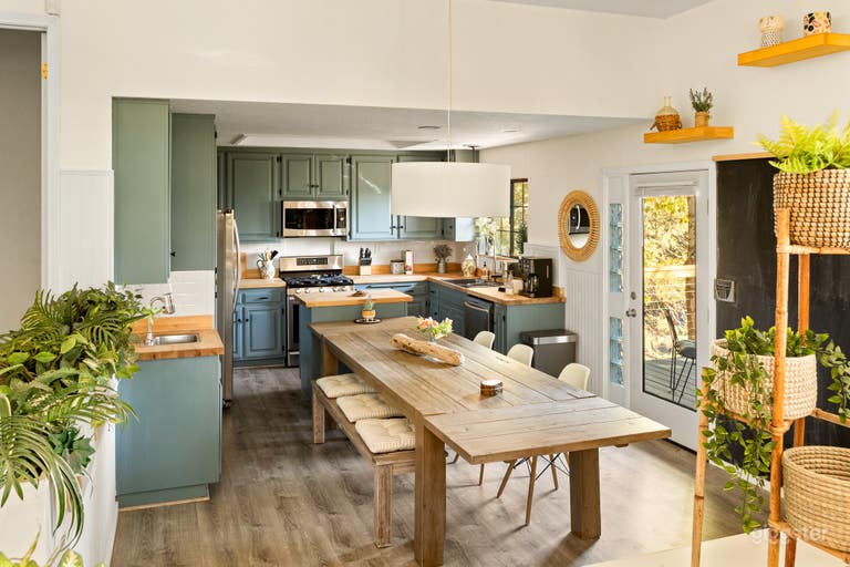  2nd floor - Sunken Kitchen and communal dining table. Wall size chalk board to extreme right. Door to private balcony  furnished (table and 4 chairs) seen to right.   