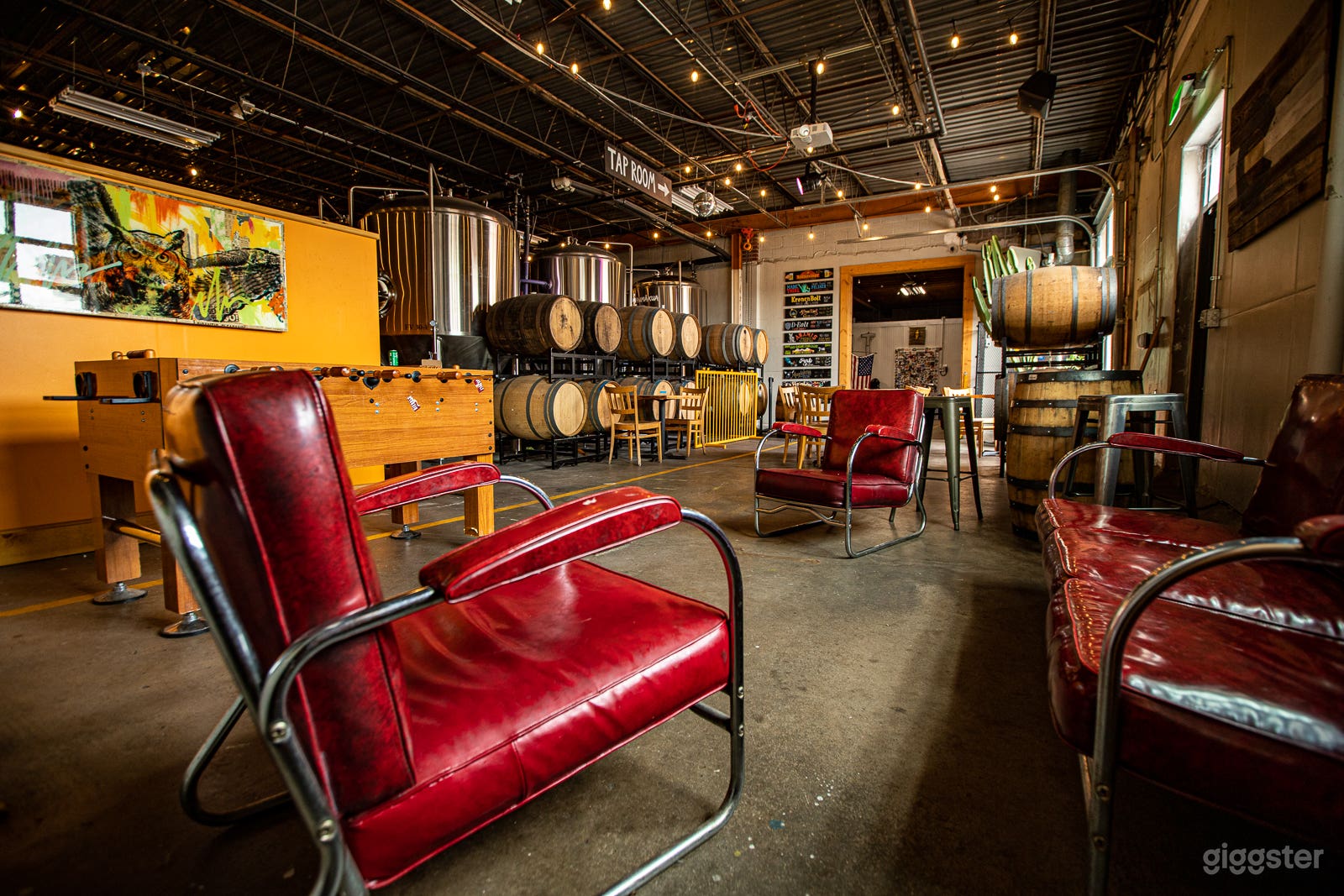 Private event space with lounge area and games nestled amongst barrels and brewing equipment. 