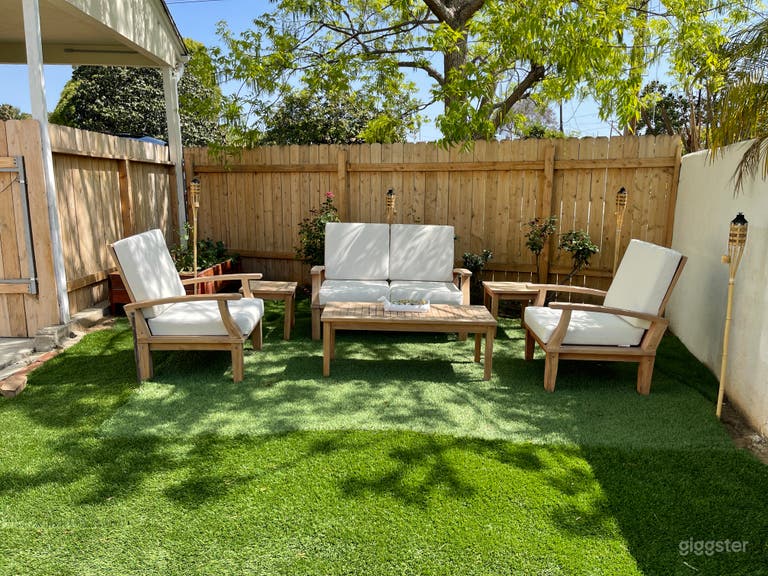  turf area with teak furniture and white cushions near fence and rose bushes 
