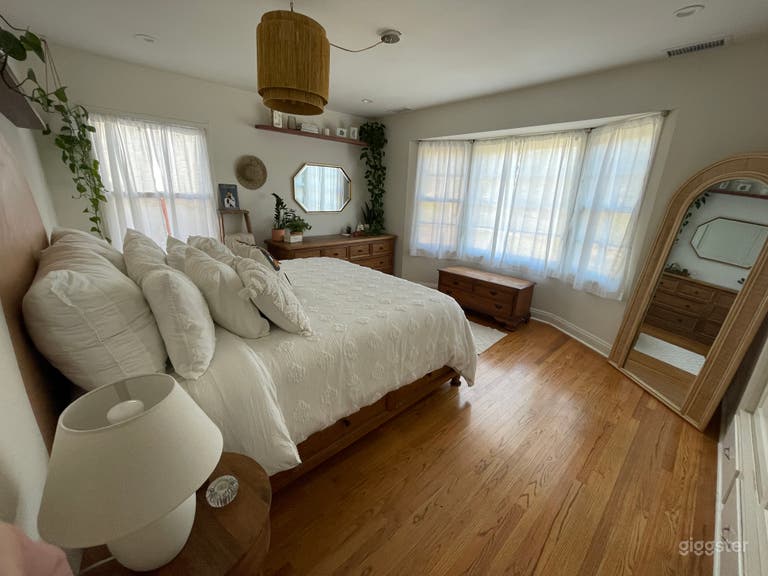  primary bedroom bohemian rattan mirror plants and bay window 