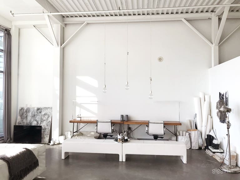  Work area decorated with white texture, retro fan, modern hanging lights.  