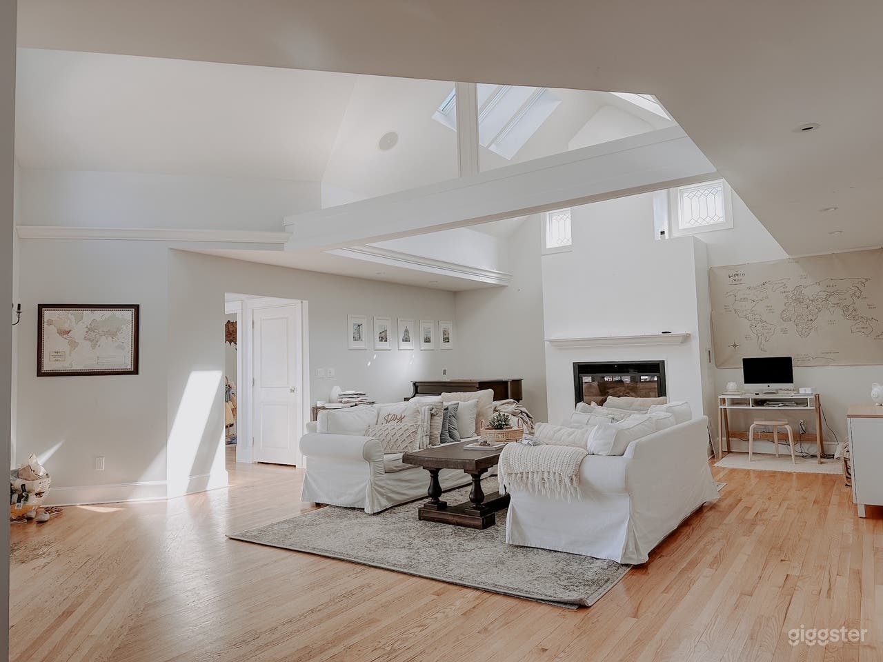 Main Living Area with 15ft vaulted ceilings, 6 skylights, baby grand piano, white walls, and crown molding. (this view is standing in the kitchen)