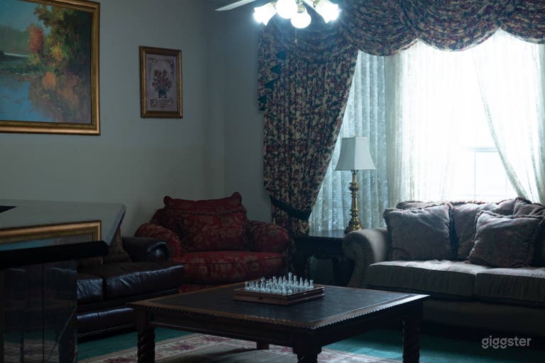  another angle of the main living room with gold trimmed paintings and 90s themed curtains 
