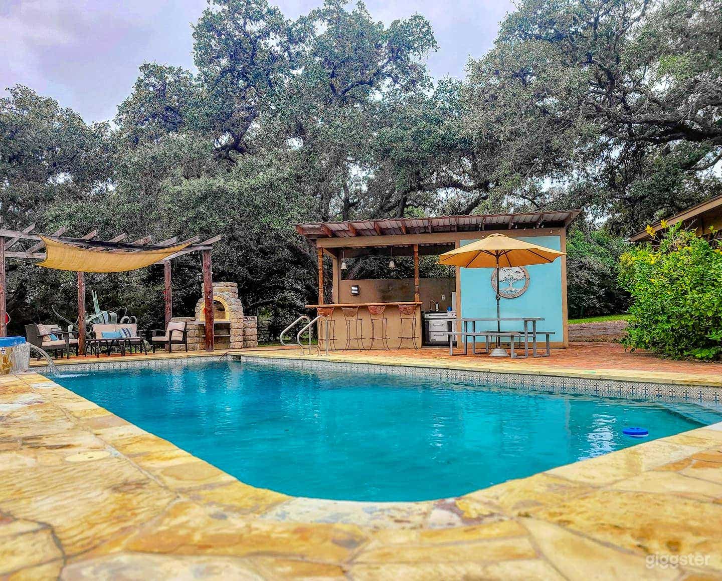 Pool area with hot tub, pergola, pizza oven, and outdoor kitchen