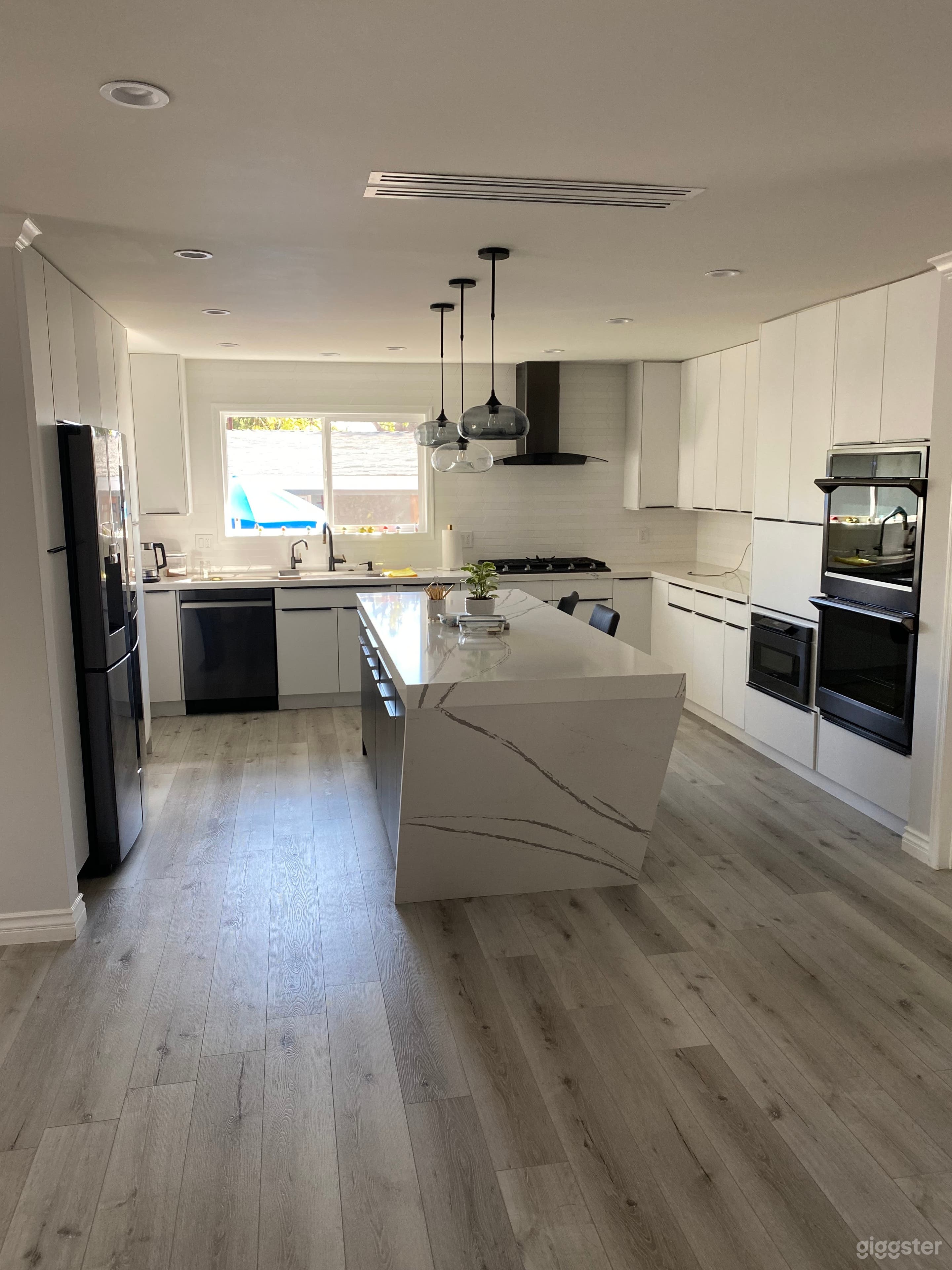 Modern kitchen with tilted Water fall island comes with double oven, counter stove, dishwasher and a refrigerator. 