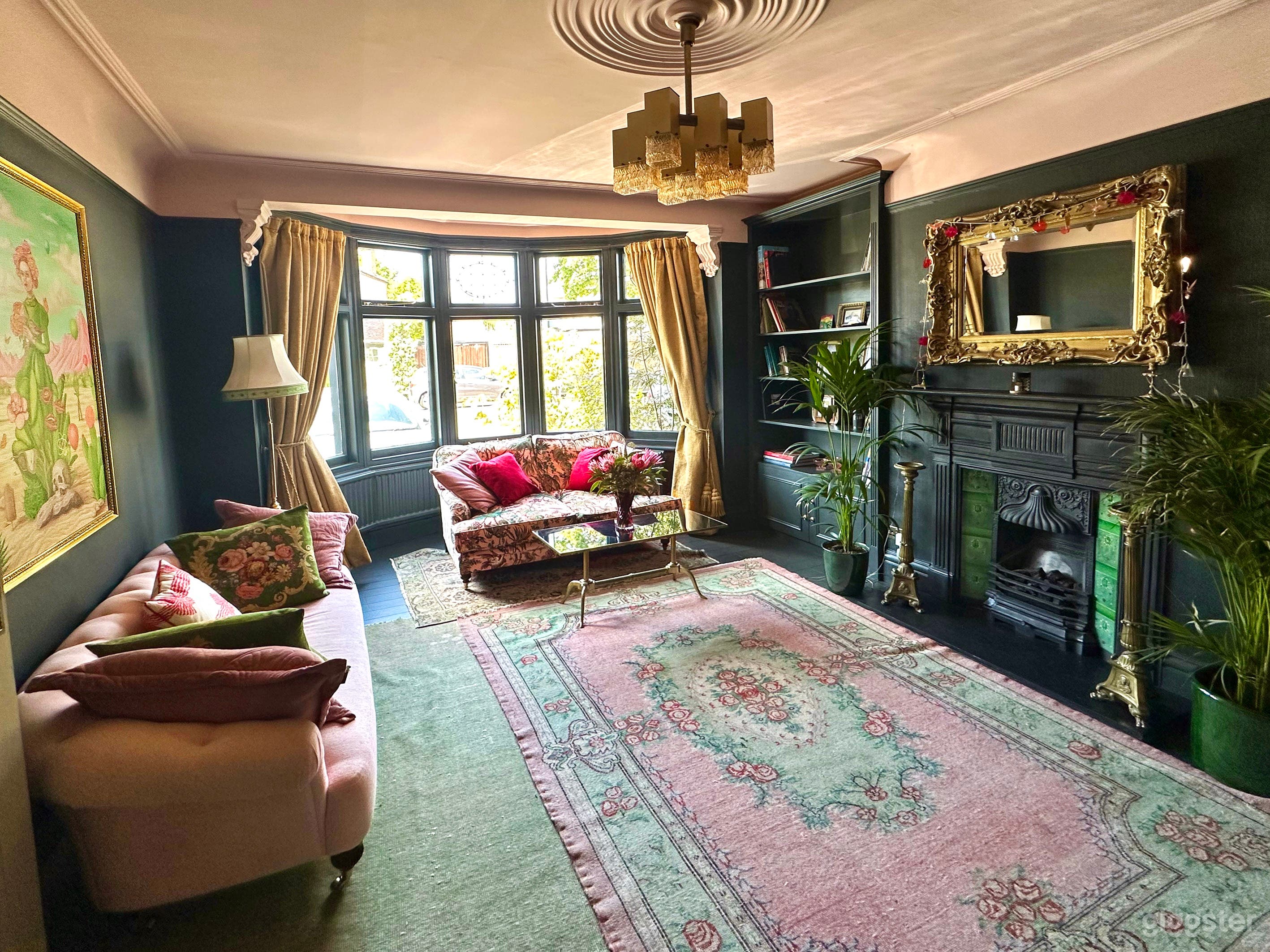 First reception room has cast iron tiles fireplace,  dark alcove shelving and wooden flooring with layered rugs