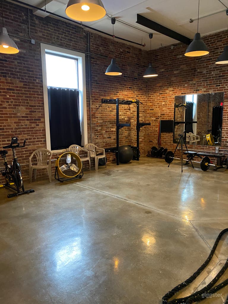  The main gym space showcasing full-length mirrors and striking exposed brick offering both function and aesthetic appeal. Perfect  for training or content creation. 