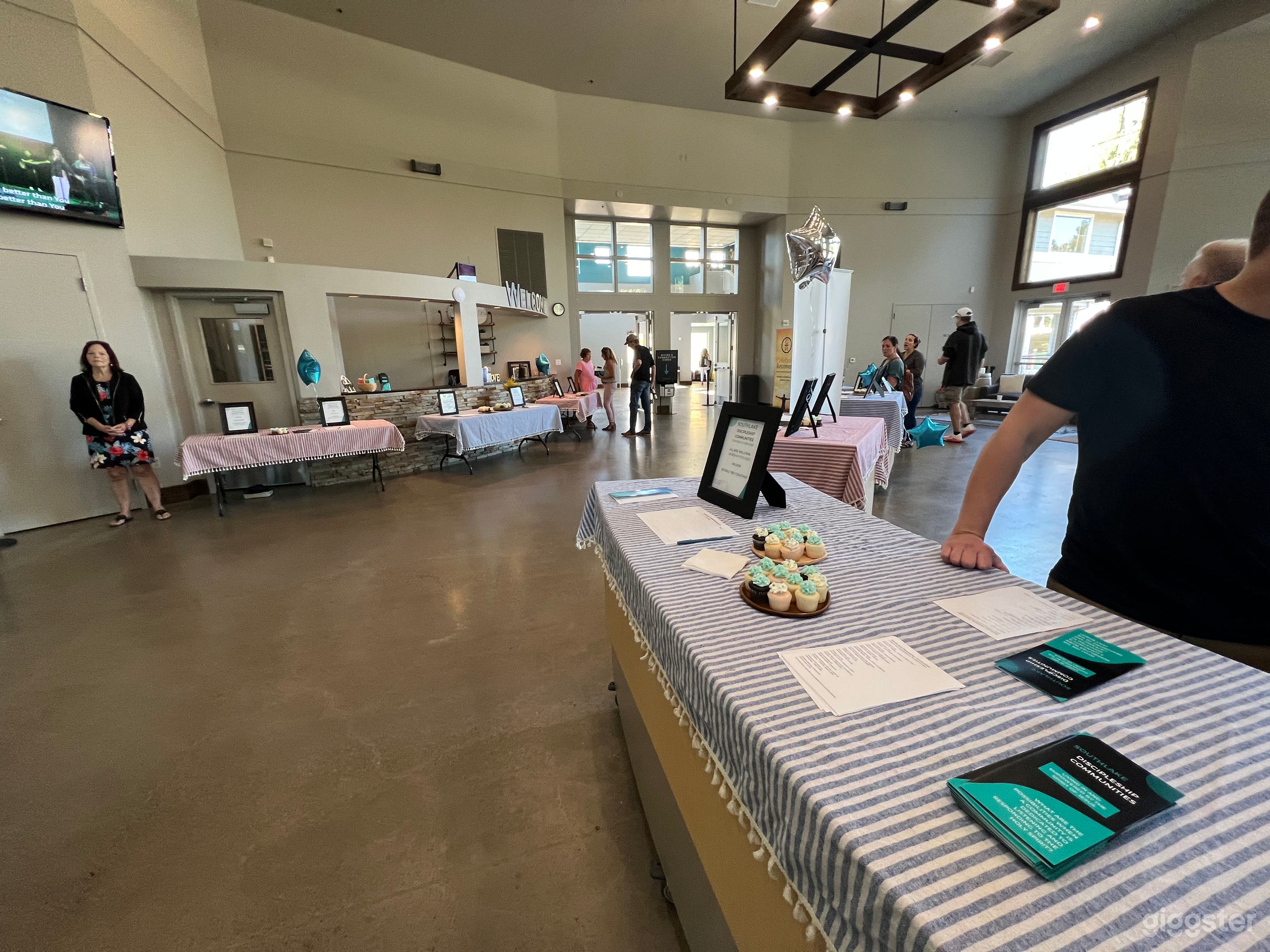 Lobby area that leads from foyer to auditorium with tall ceilings and custom farmhouse/modern chandeliers. 