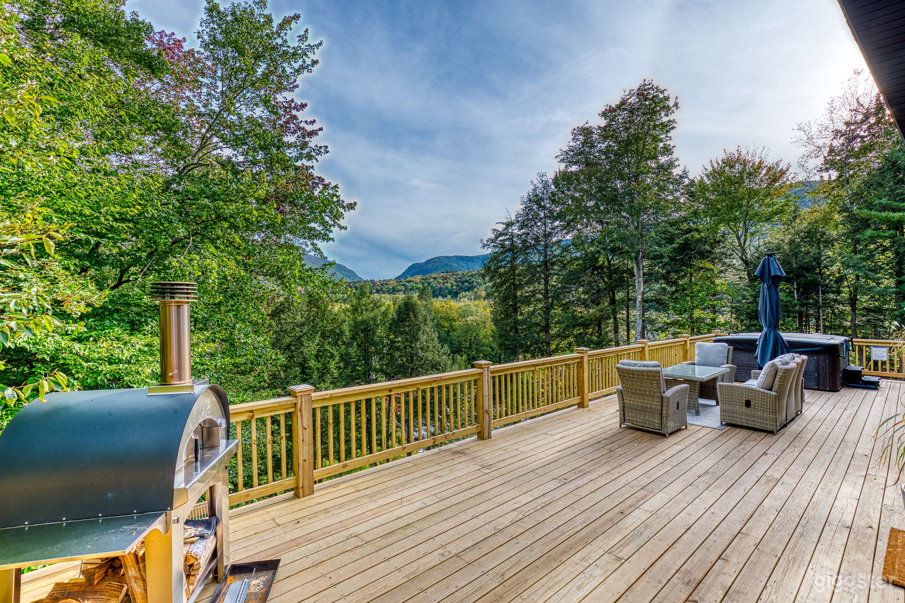 Large deck with pizza oven, dining table, reclining chairs and hot tub