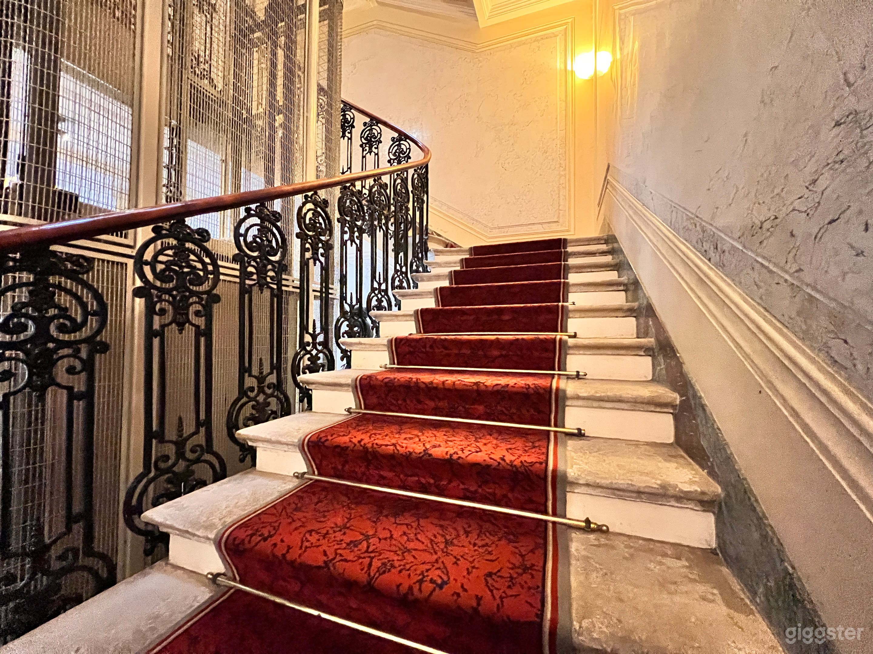Grand Staircase – A historic Haussmannian staircase with ornate iron railings and a red-carpeted ascent.