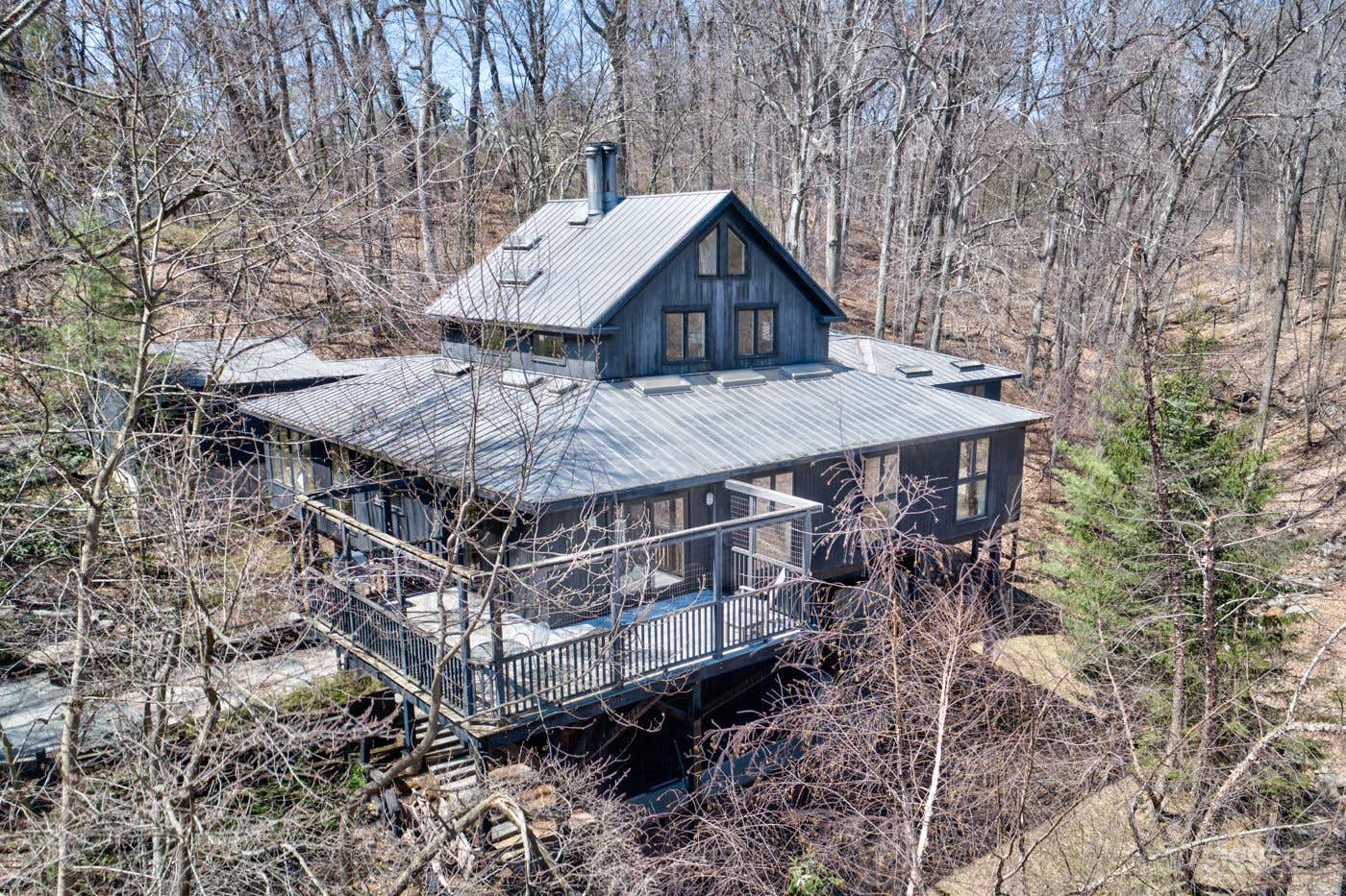 Our house is like a treehouse. Walk out basement with columns supporting main floor and smaller top floor. Windows look out onto trees.
