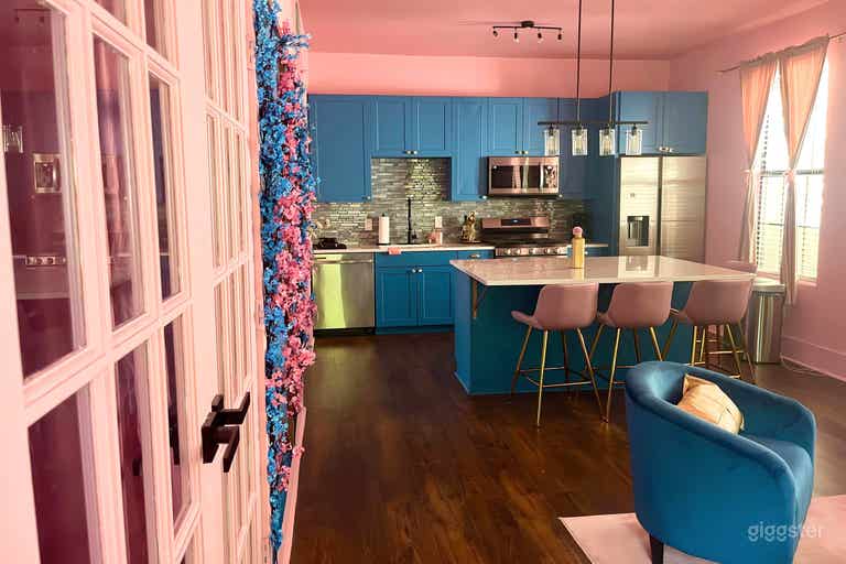 Vibrant dining area featuring a modern kitchen with bold blue cabinets, a sleek island with comfortable pink barstools. 