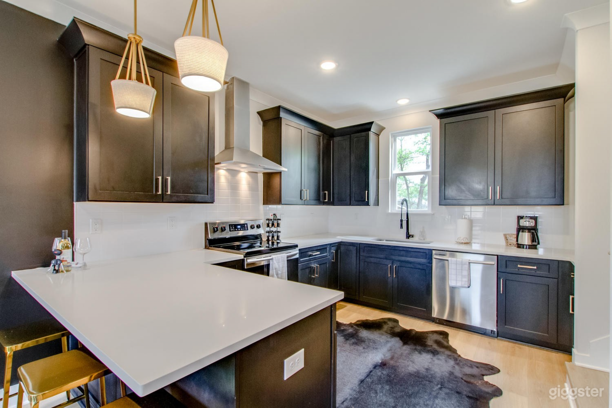 Large kitchen w/stainless steel appliances, quartz countertop and black cabinets.
