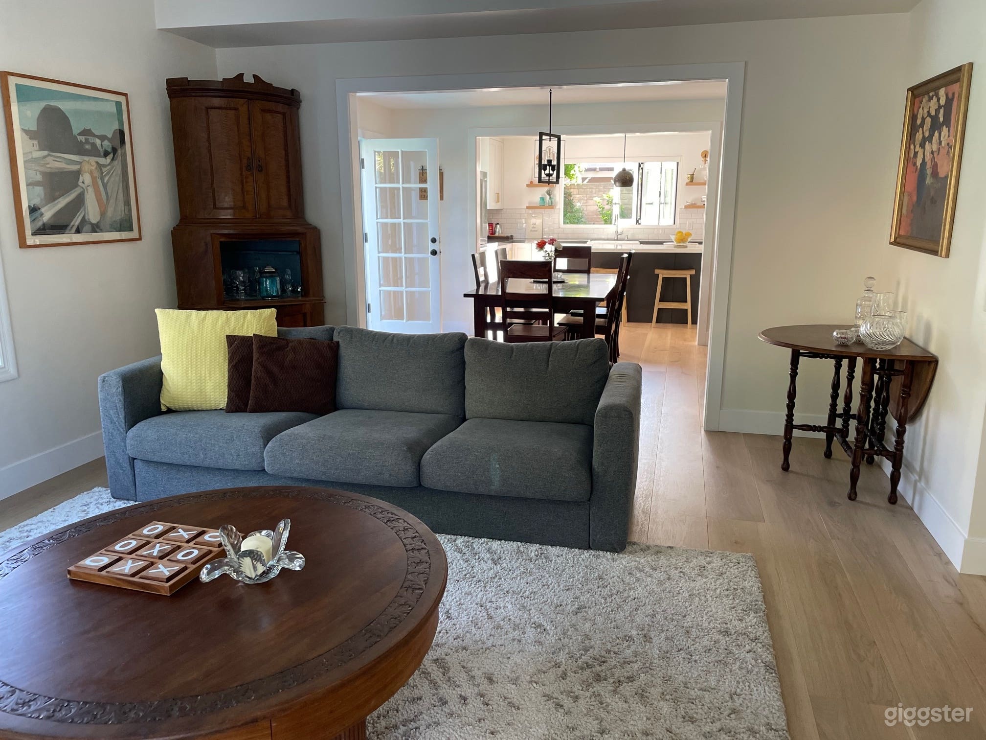 The living room has high ceilings, a window seat, and looks all the way through the dining room, to the kitchen, and outside a tri-fold window.