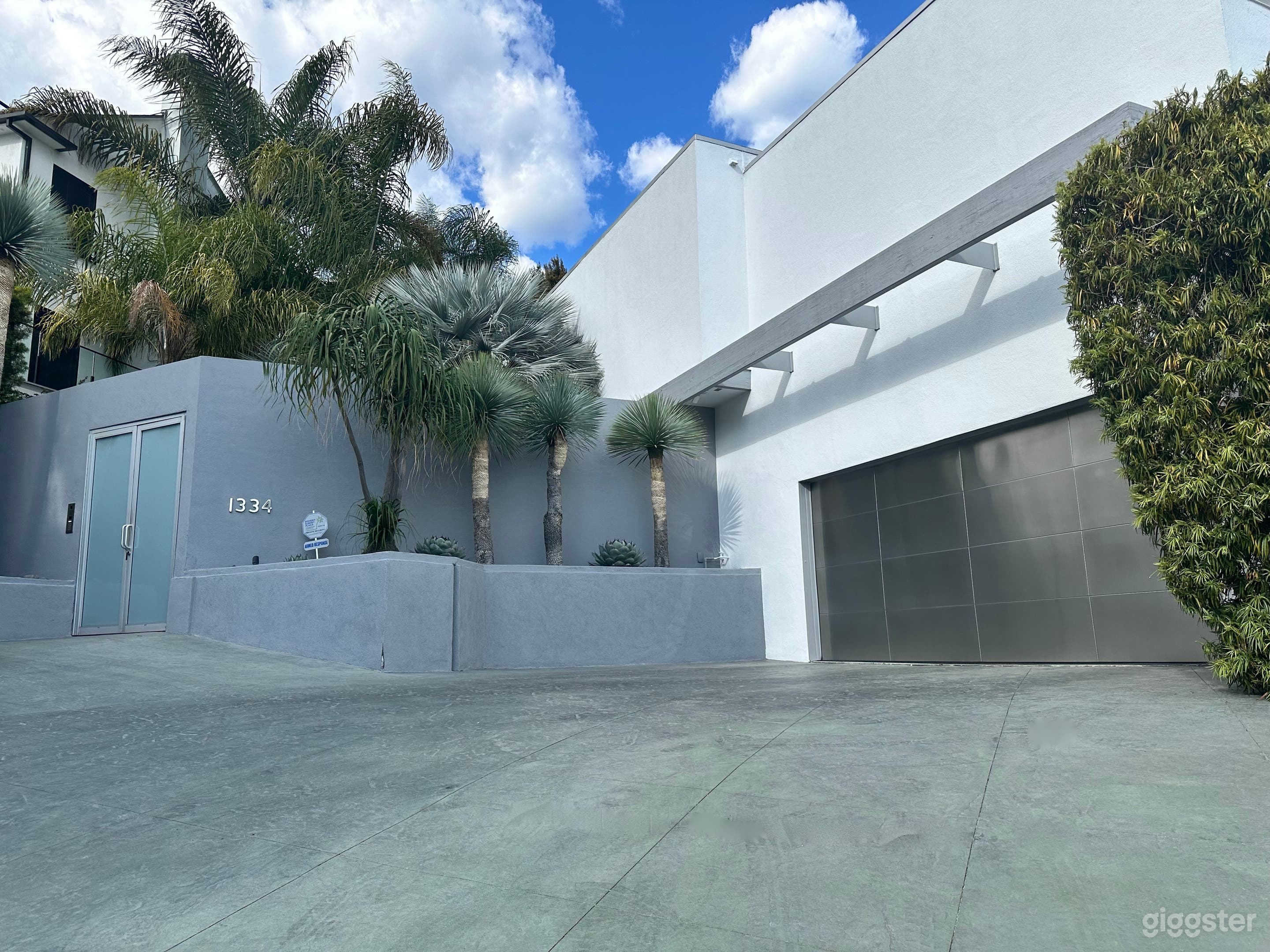 Front exterior with expansive driveway, desert landscape and West Hollywood views. 