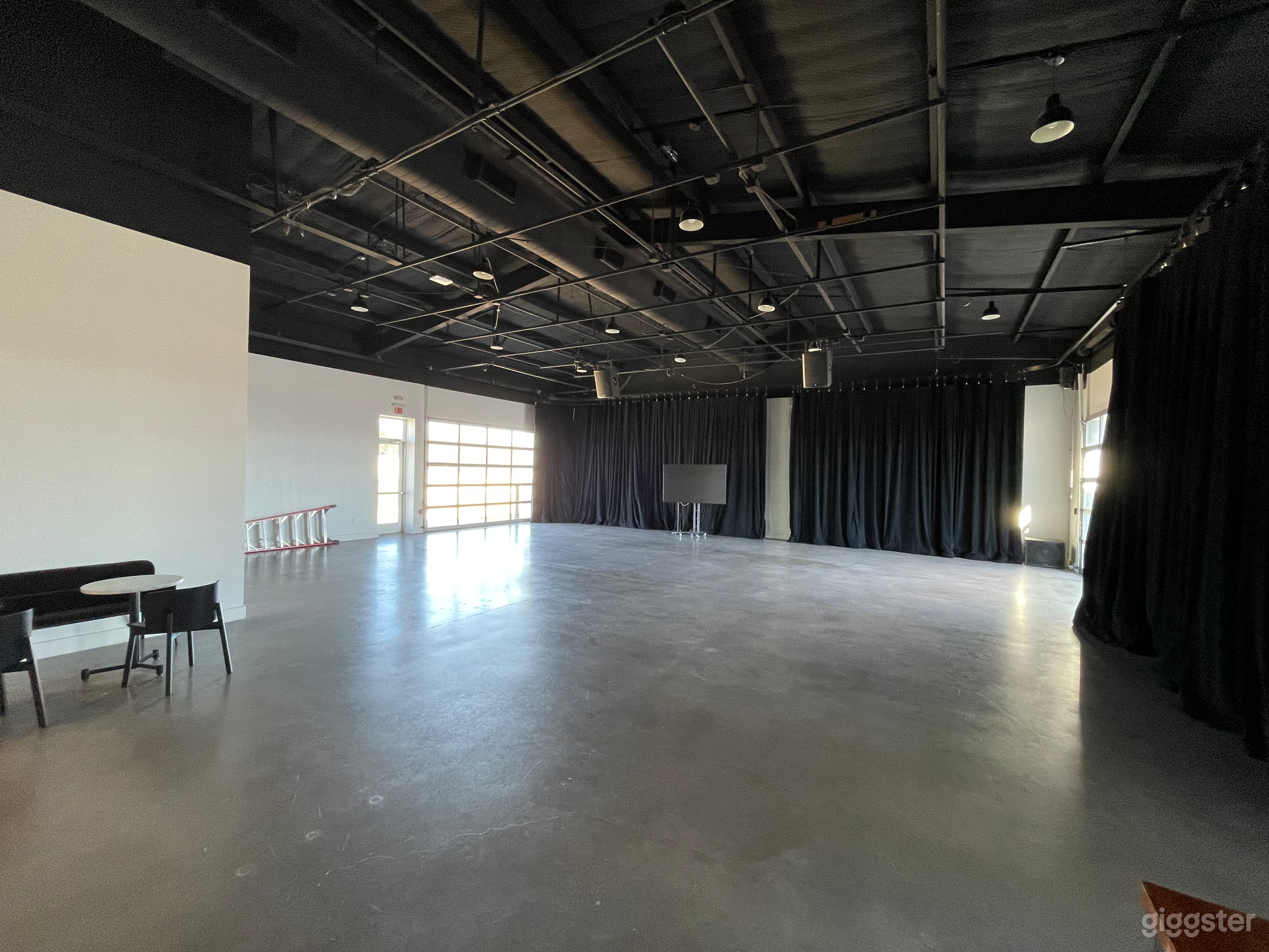 Concrete floors and glass garage doors, with white walls behind the curtains.