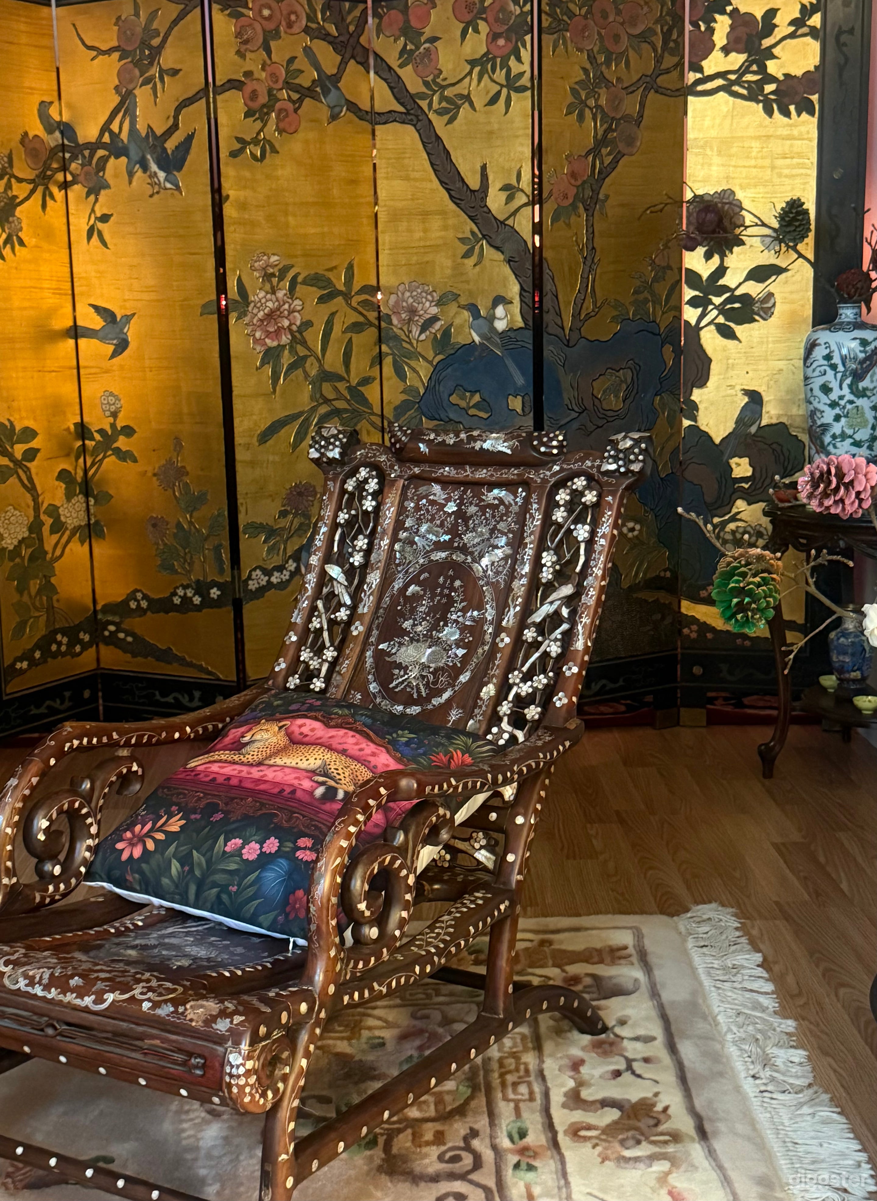 Qing Dynasty armchair with exquisite mother-of-pearl inlay. Floral and bird motifs carved from iridescent shell, glowing in soft blues, pinks, and golds under warm light. A rare piece for any vintage oriental shoot.