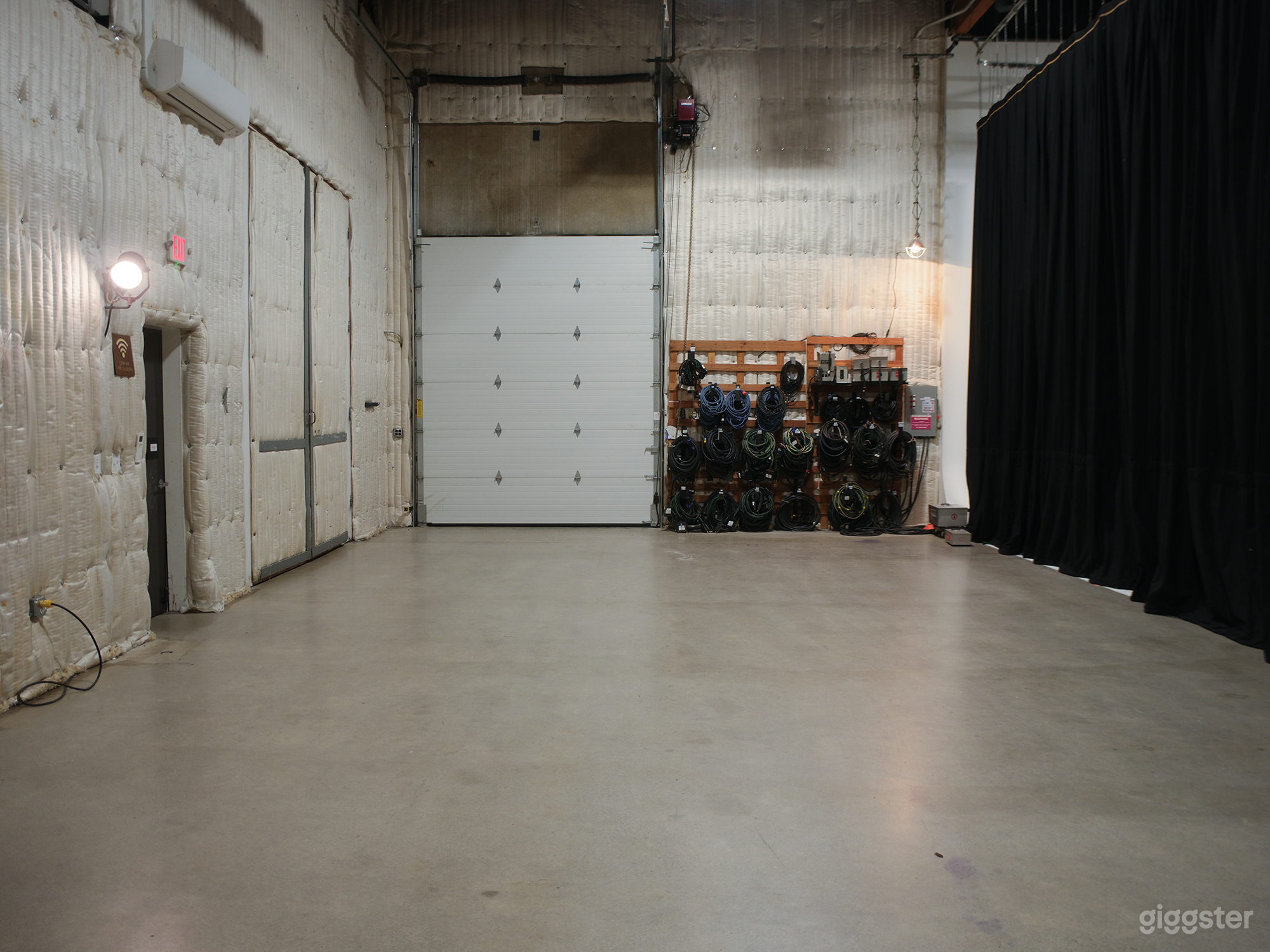 Spacious Staging and Loading Area: We have an expansive, open staging area with high ceilings and a minimalist aesthetic. The concrete floor and padded walls create a versatile space suitable for storage, staging, or production needs.