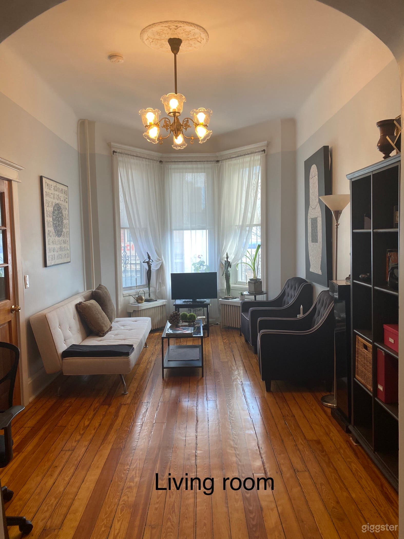Living room with 12-foot ceiling, antique bronze chandelier, hardwood floors, bay windows and the original artwork (paintings and sculpture)