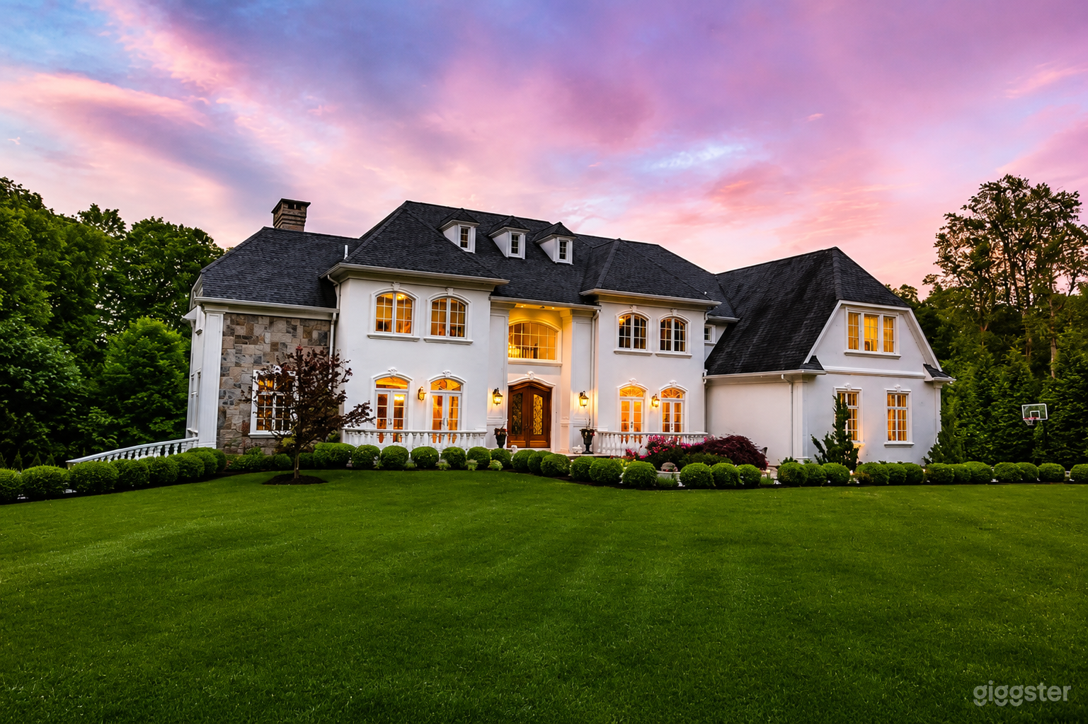 Front exterior view of the estate showcasing its elegant architecture, manicured lawn, and impressive arrival experience.