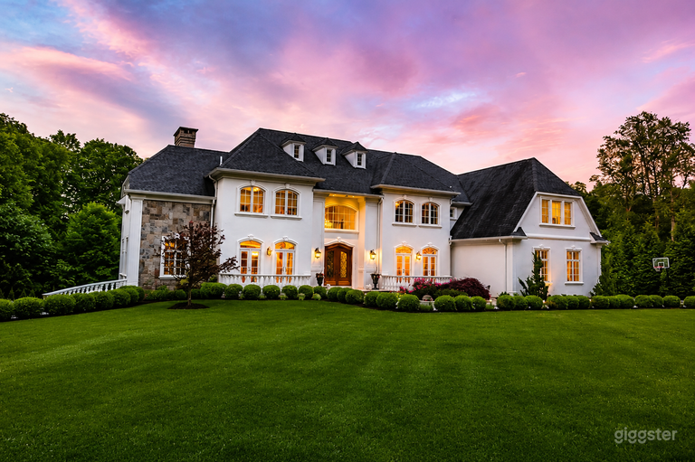  Front exterior view of the estate showcasing its elegant architecture, manicured lawn, and impressive arrival experience. 