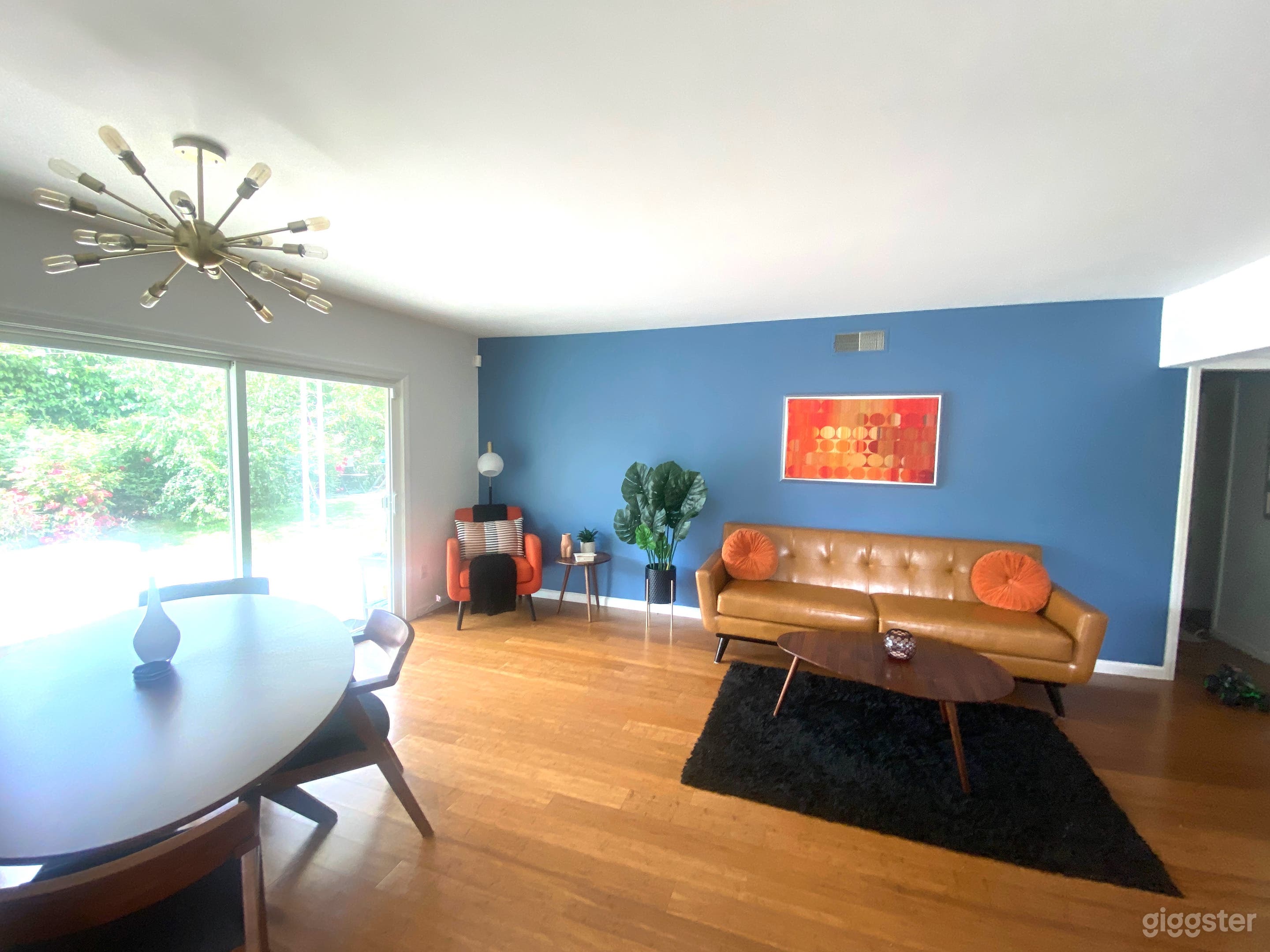 A midcentury dream room! Entertaining area, sliding glass doors leading to the pool. Oval midcentury dining table and custom sputnik light fixture.