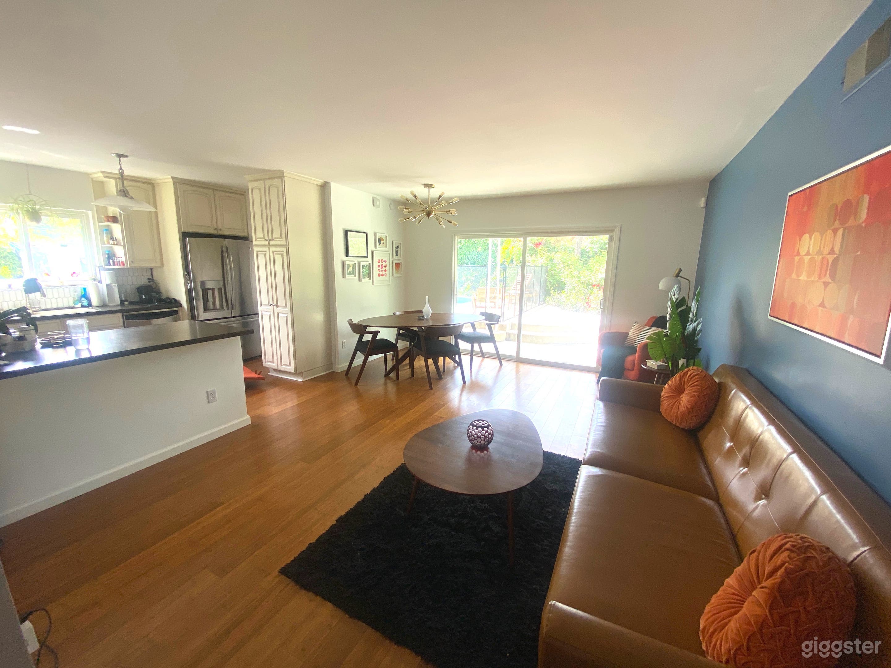 View of open marble counter top kitchen in entertaining area, leading to sliding glass doors and pool. 