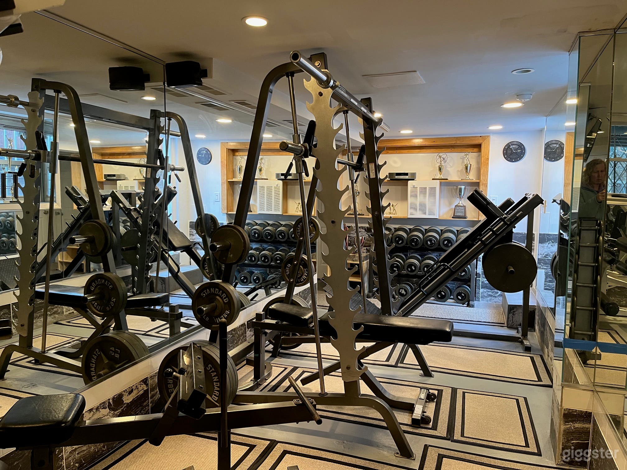 Gym showing equipment and dumb-bell rack with trophies 