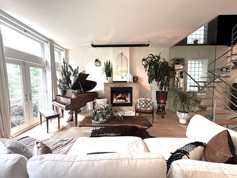  Plant-filled piano lounge with baby grand, fireplace, projection screen, and floating staircase. 