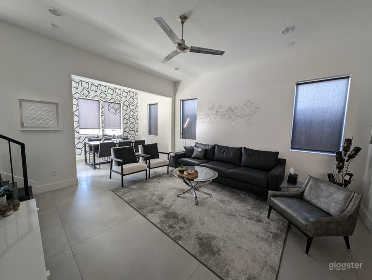  An extra-long black leather sofa is paired with a mid-century modern silver alligator chair in the living space. 