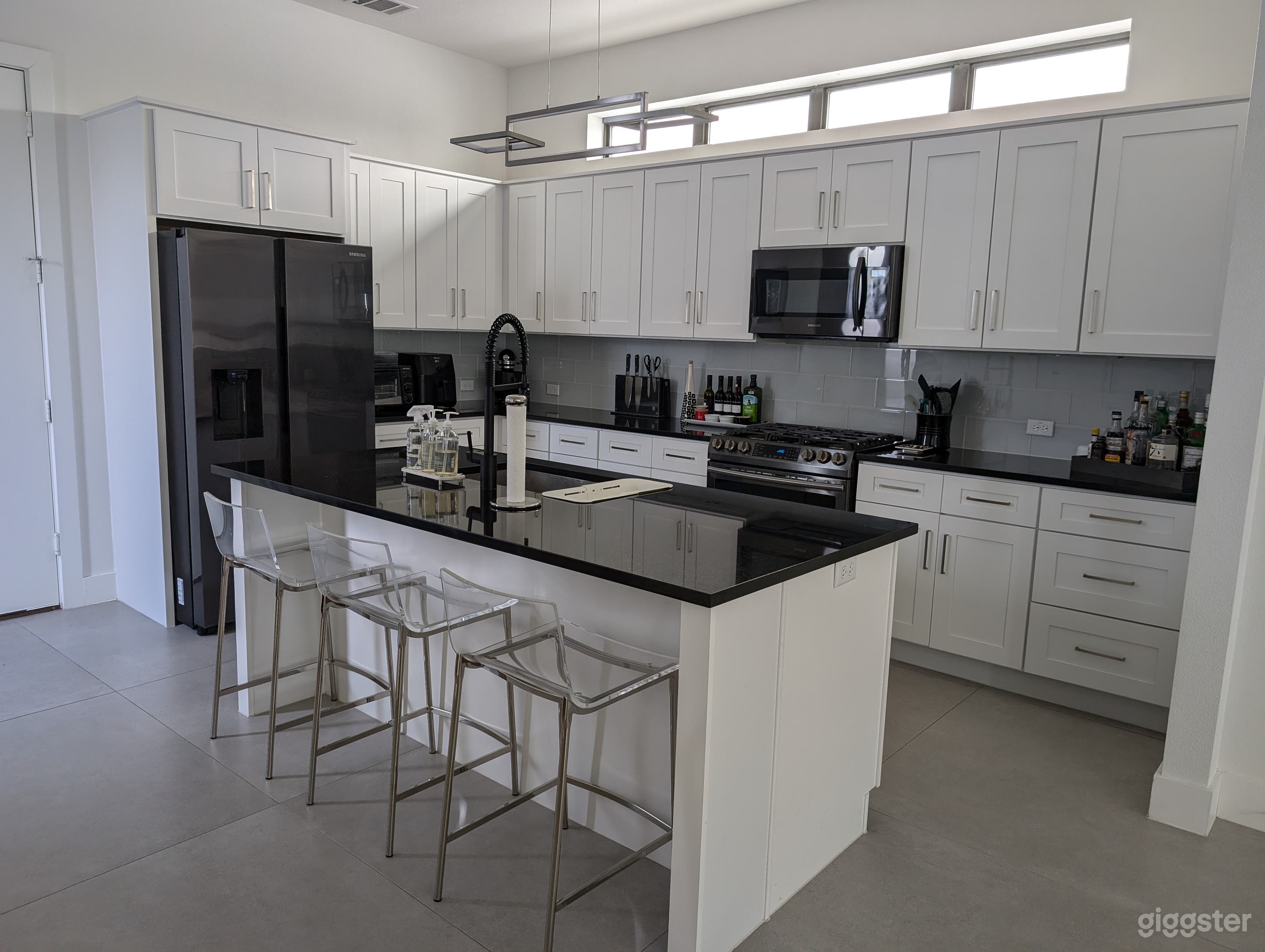An open concept kitchen with tons of counter space and an island sink is great for filming. The kitchen is well-stocked with pots, pans, serving pieces, and small appliances.