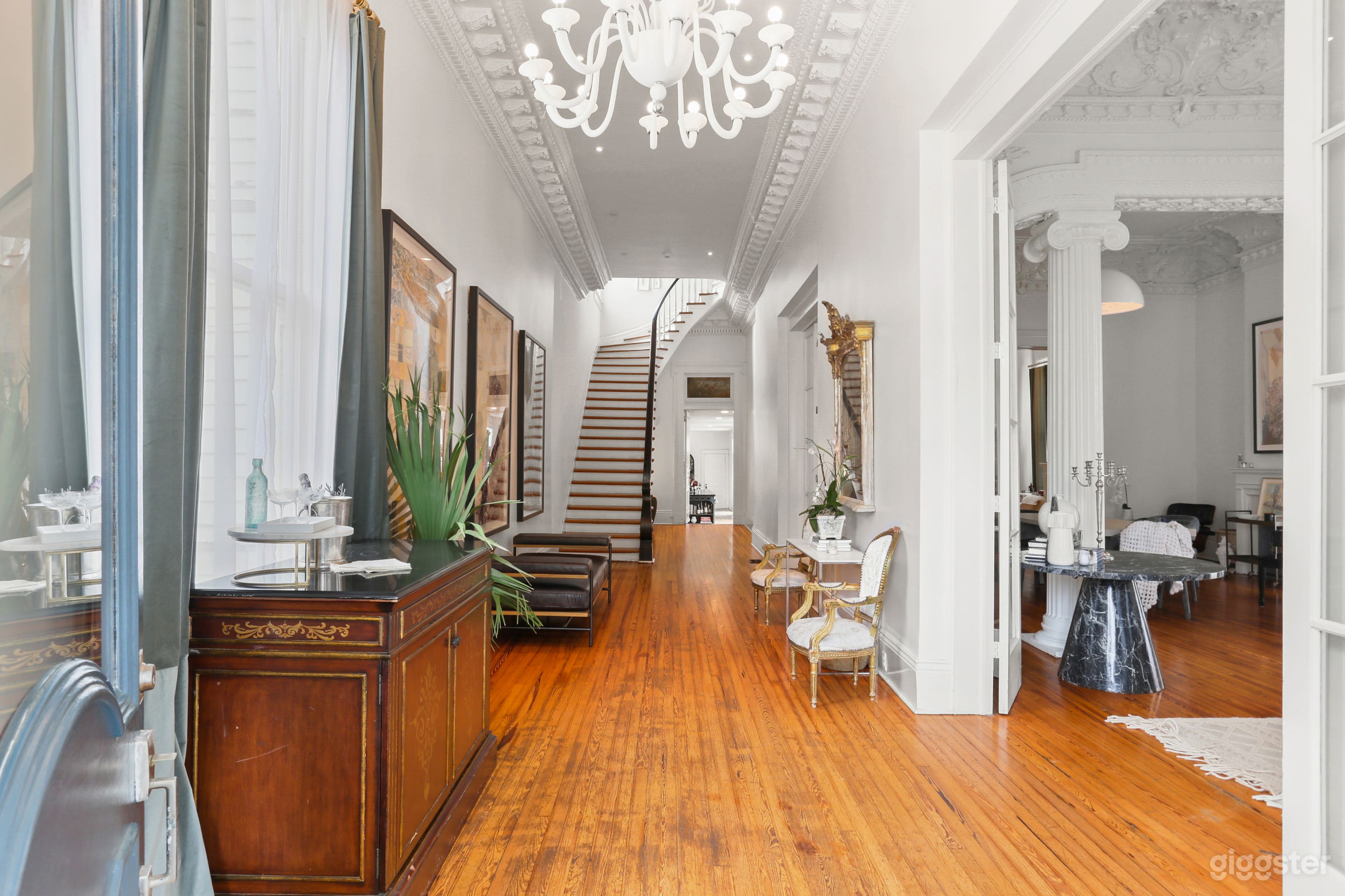 Enter the grand hallway of this historic New Orleans estate, where a sweeping staircase, intricate crown molding, and an iconic Italian chandelier create a breathtaking first impression for your guests.