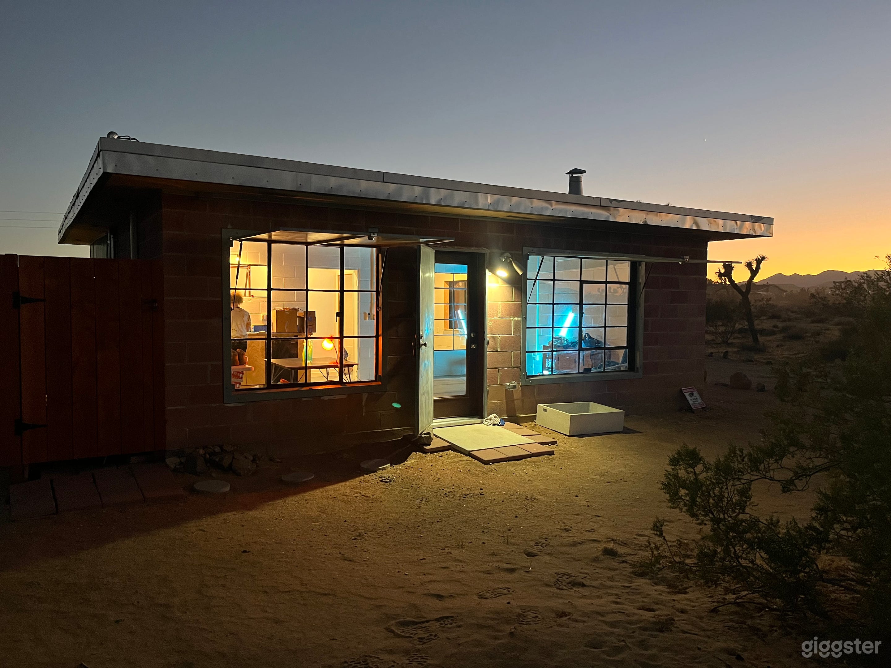 1957 homestead cabin with block walls and steel case windows at sunset.
