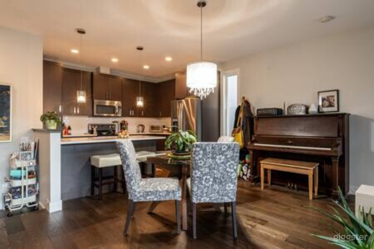 Open concept kitchen/dining with antique upright piano and modern chandelier.
