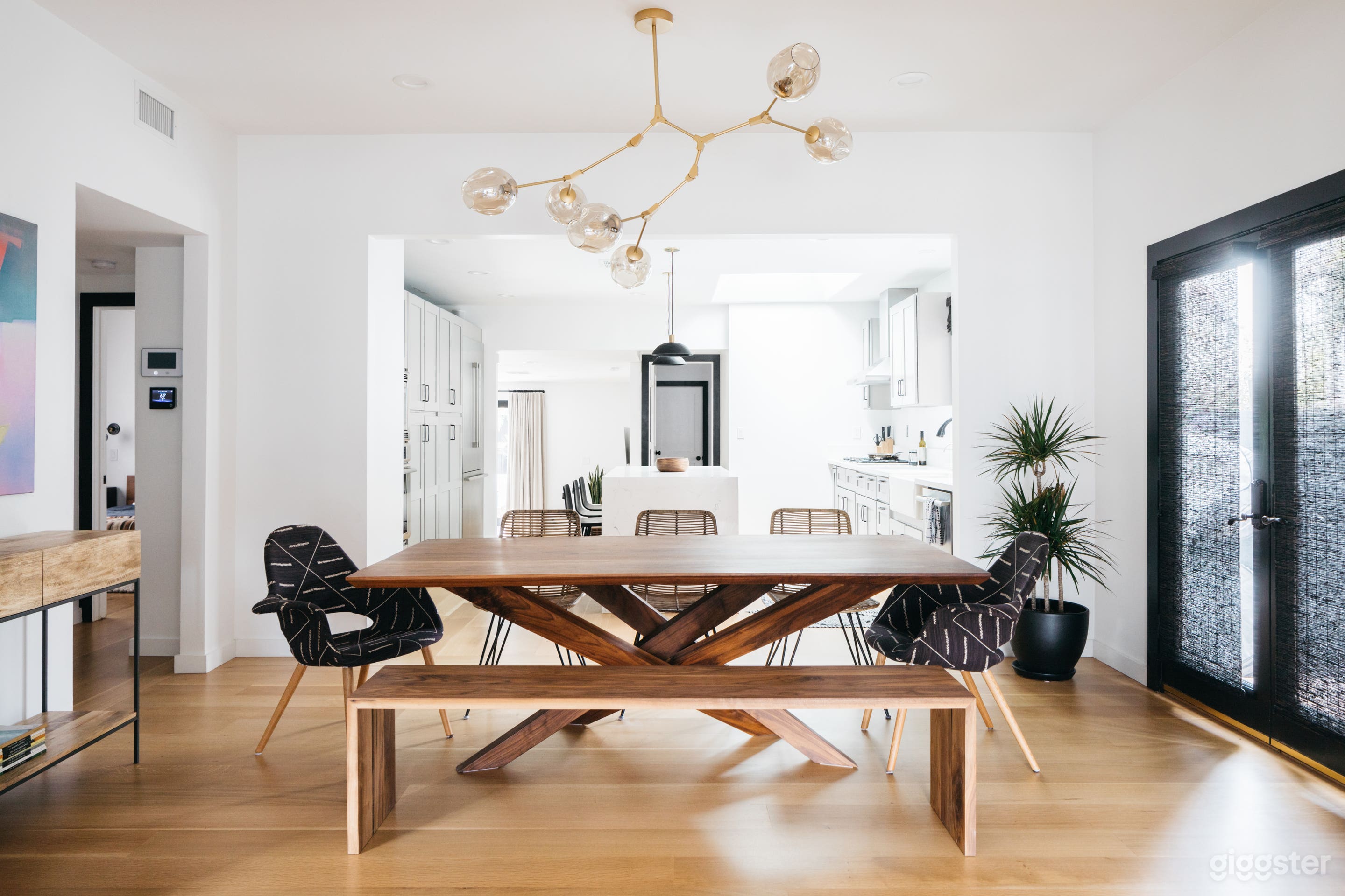 Open dining room with custom modern walnut dining table and custom chairs. Dining rooms opens to both front living room and kitchen with ample light from both spaces.