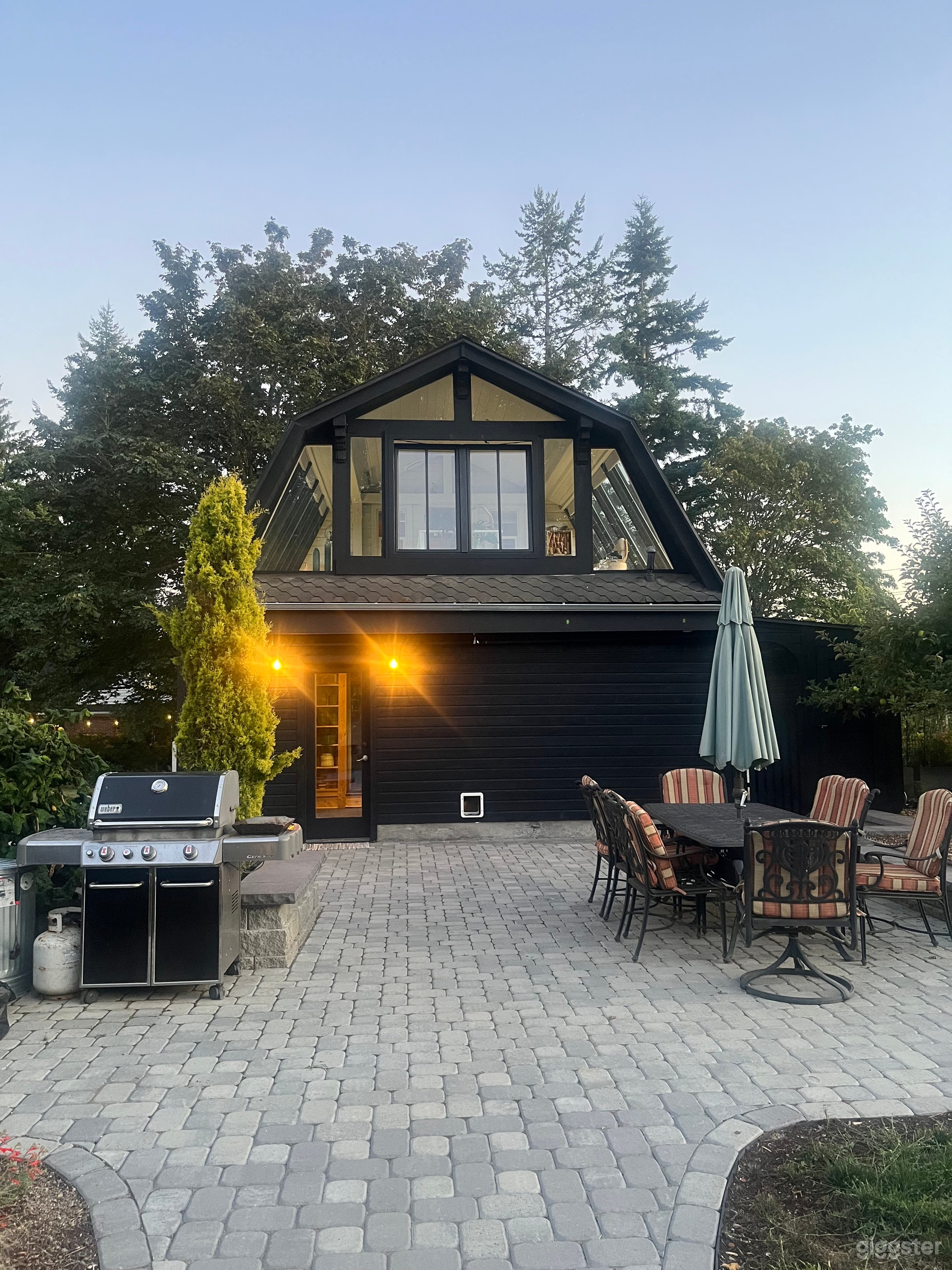Spacious stone-paver patio with atmospheric night lighting, a large dining set, and professional BBQ. Perfect for outdoor lifestyle scenes, cast breaks, or intimate evening gatherings.