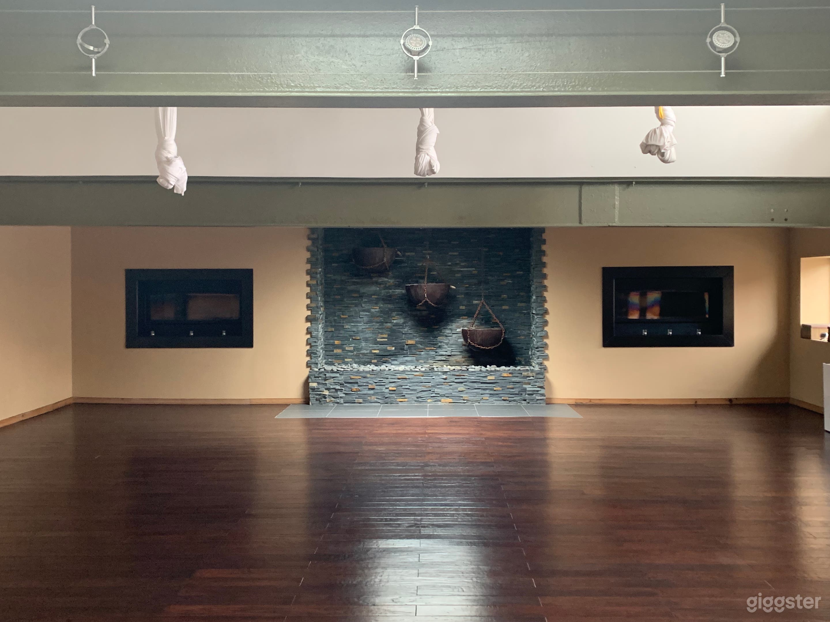 Main studio space with exposed beams, custom waterfall wall, in-laid gas fireplaces and aerial silks (they can be removed)