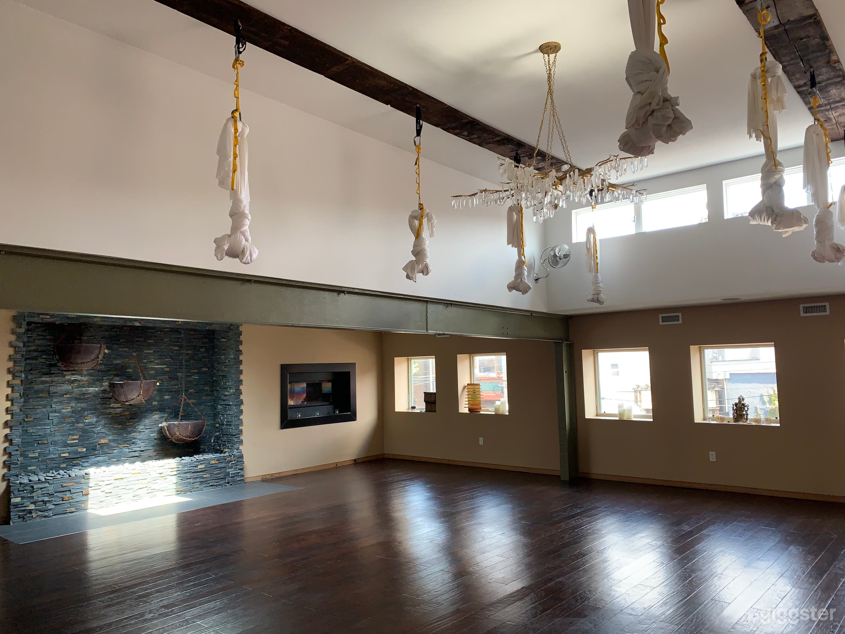 Main studio space with exposed beams, high ceilings, skylights (there are 2 other that are not visible in pic), custom waterfall wall, in-laid gas fireplaces crystal chandelier and aerial silks (they can be removed)