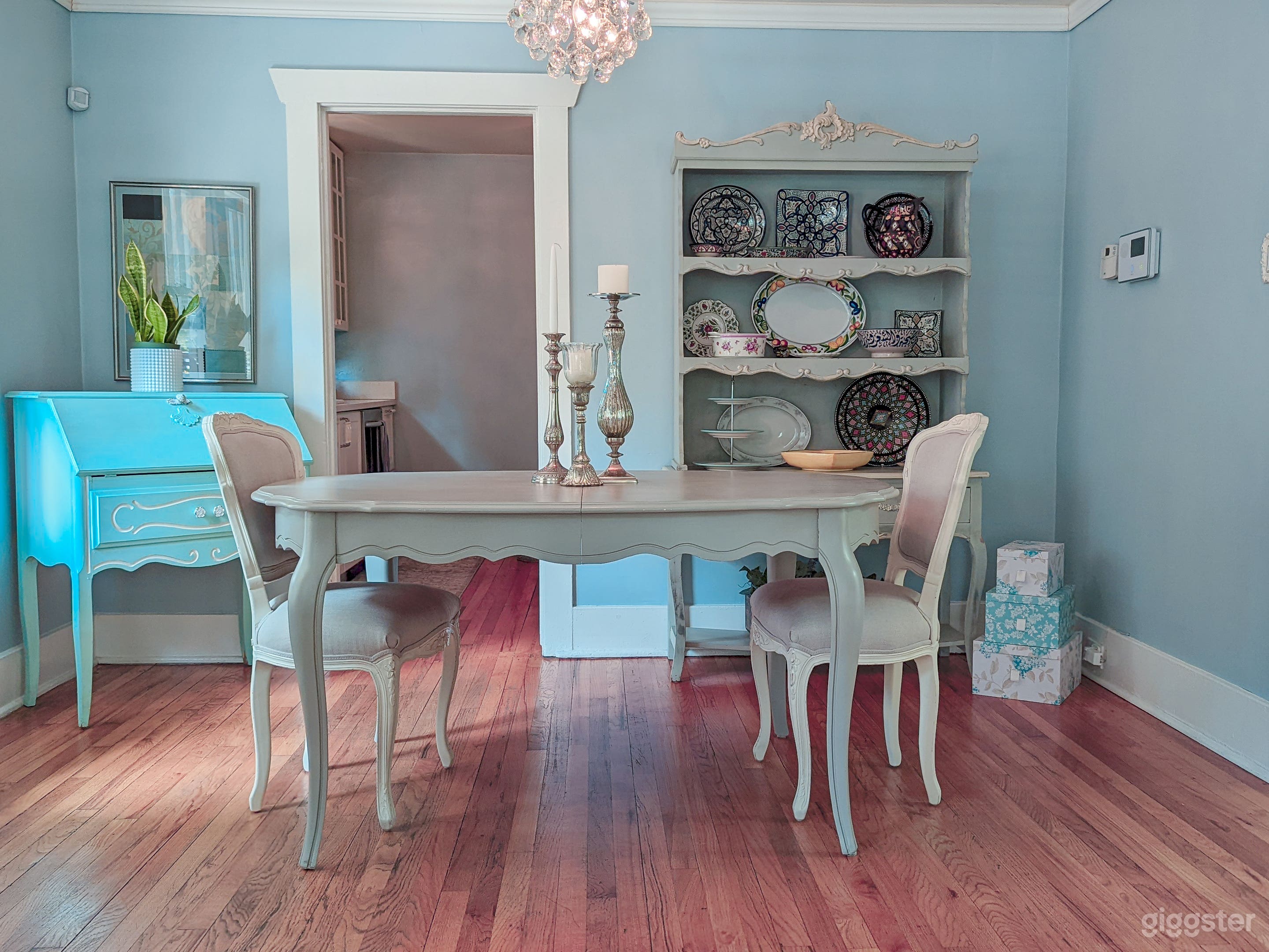 Dining area with French table, vintage bureau and various plateware/artifacts from around the world. 