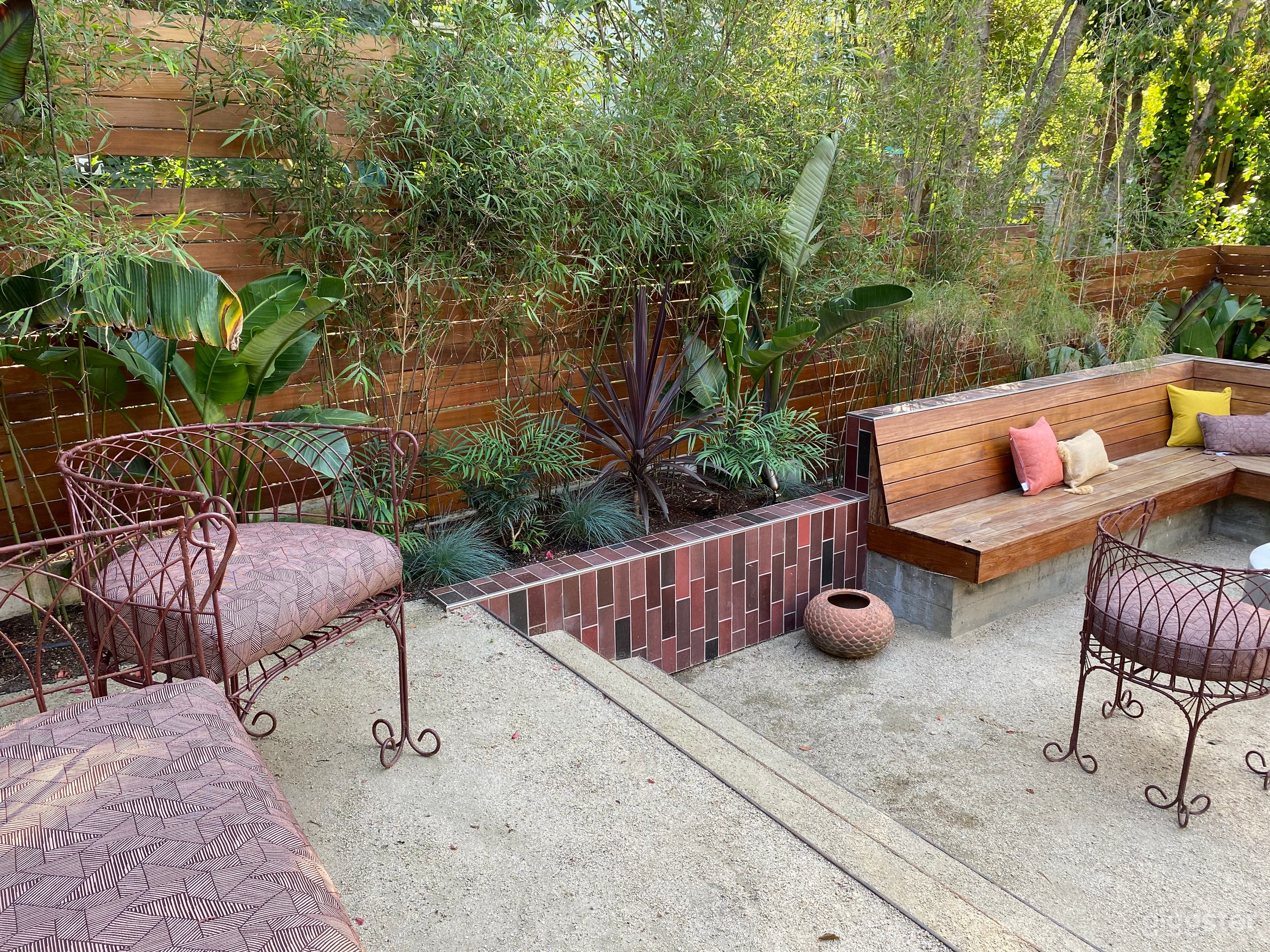 Unique, colorful backyard with terraced spaces, Heath tile, lush tropical plants, fire pit. 