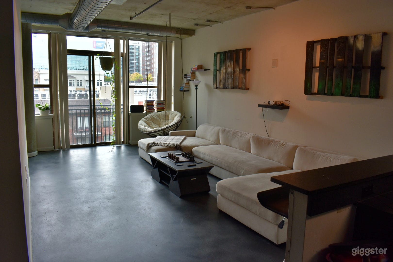 Living room with a chic minimalistic design featuring an oversized couch and hanging papasan chair