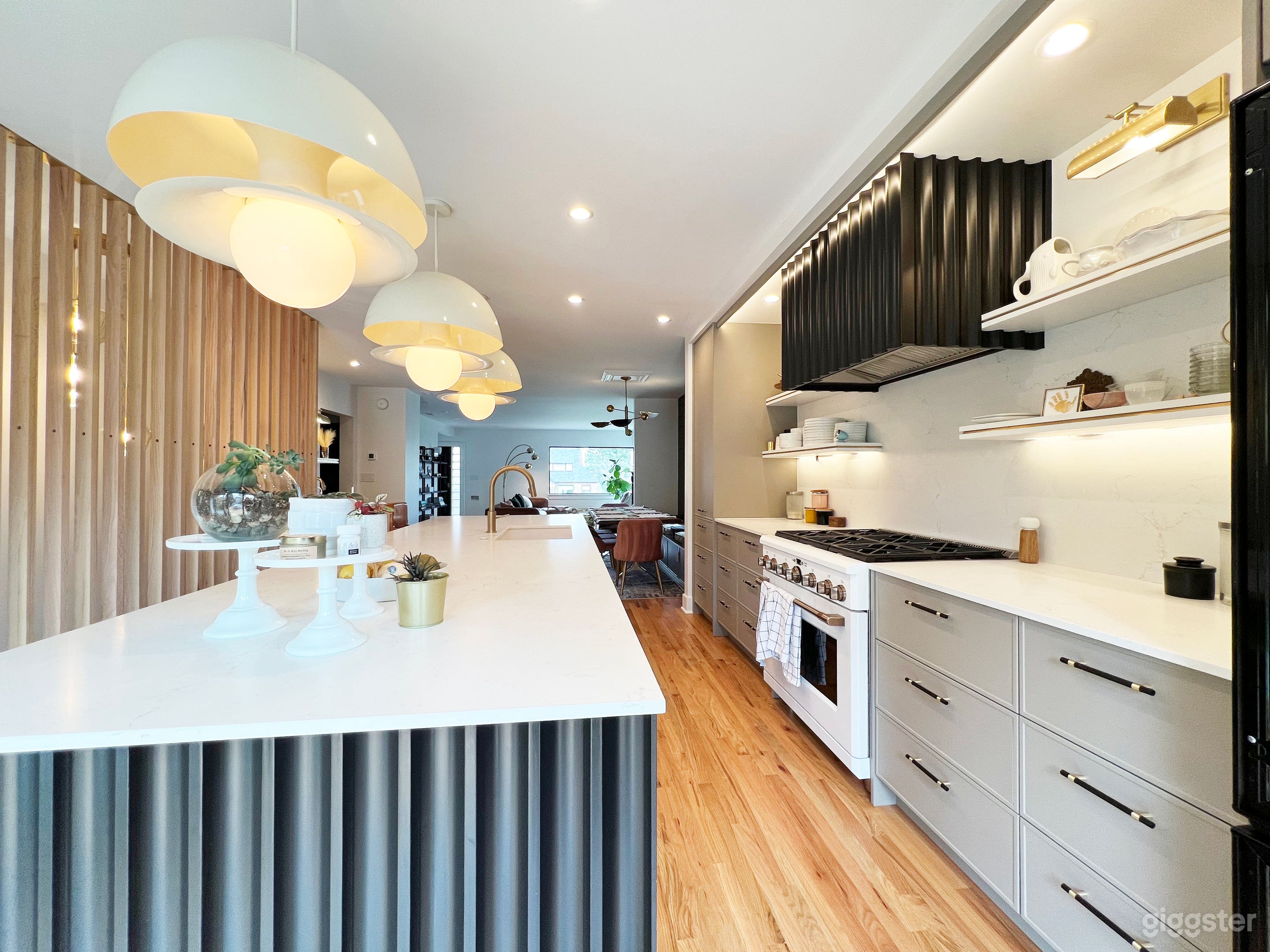 Show stopper kitchen with custom design details like this black wood channeled hood and island. Huge kitchen island with white marble counter top.