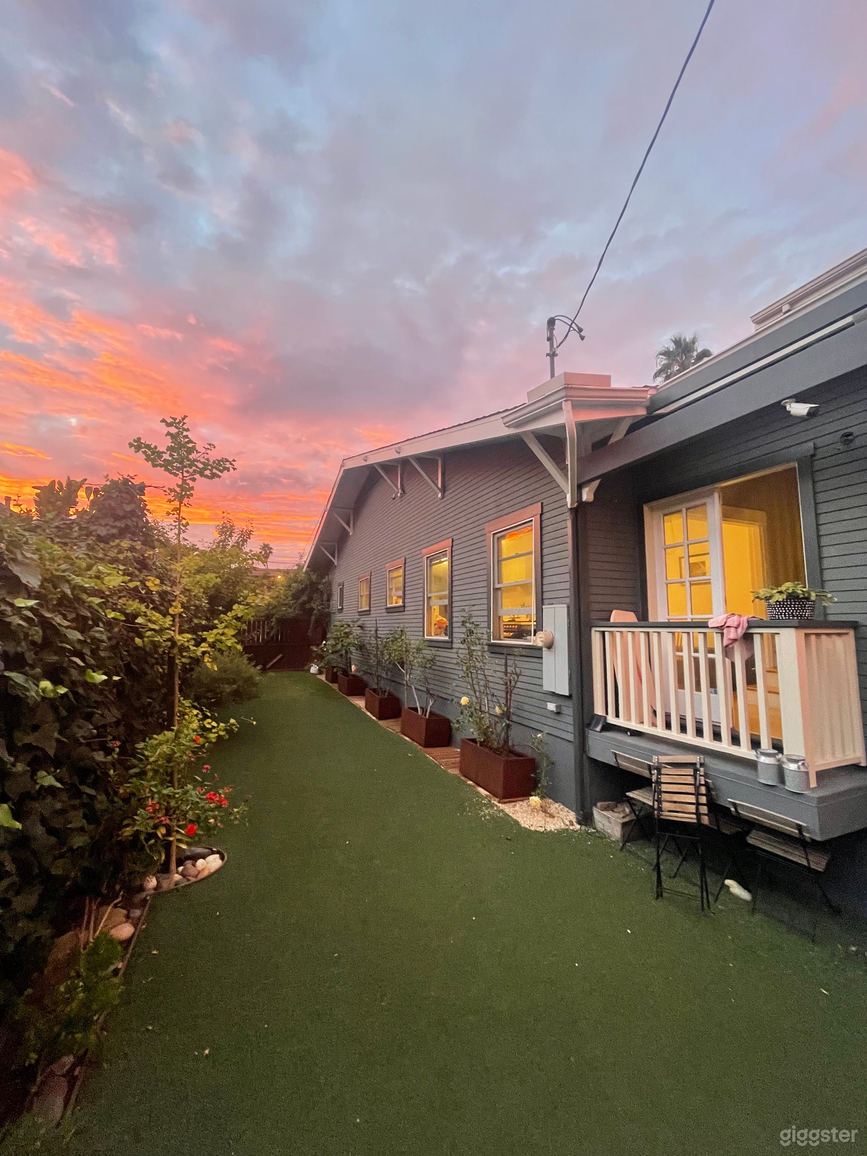 L-shaped backyard with part turf and flagstone.  There are maple, fig, and gingko trees, along with honeysuckle and jacaranda along the margin of the yard. Planted roses and overgrown ivy give the yard a tranquil feel.